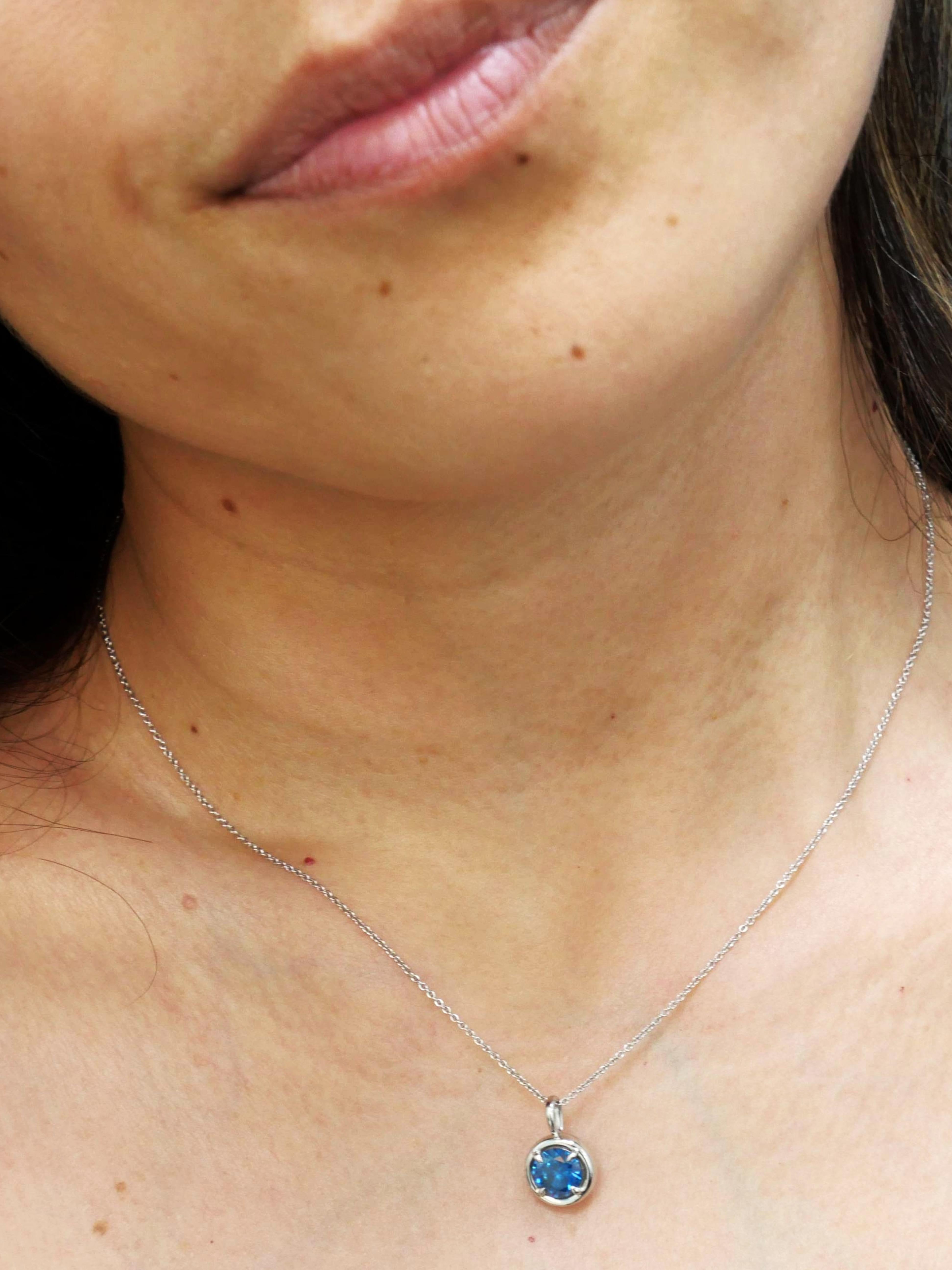 Un classique moderne avec un côté riche et terreux. Notre pendentif Solstice est serti à la main en or blanc 14K. Le diamant bleu de 1,00 carat est fixé par des griffes d'aigle et encadré par des parois latérales doucement arrondies qui mettent en