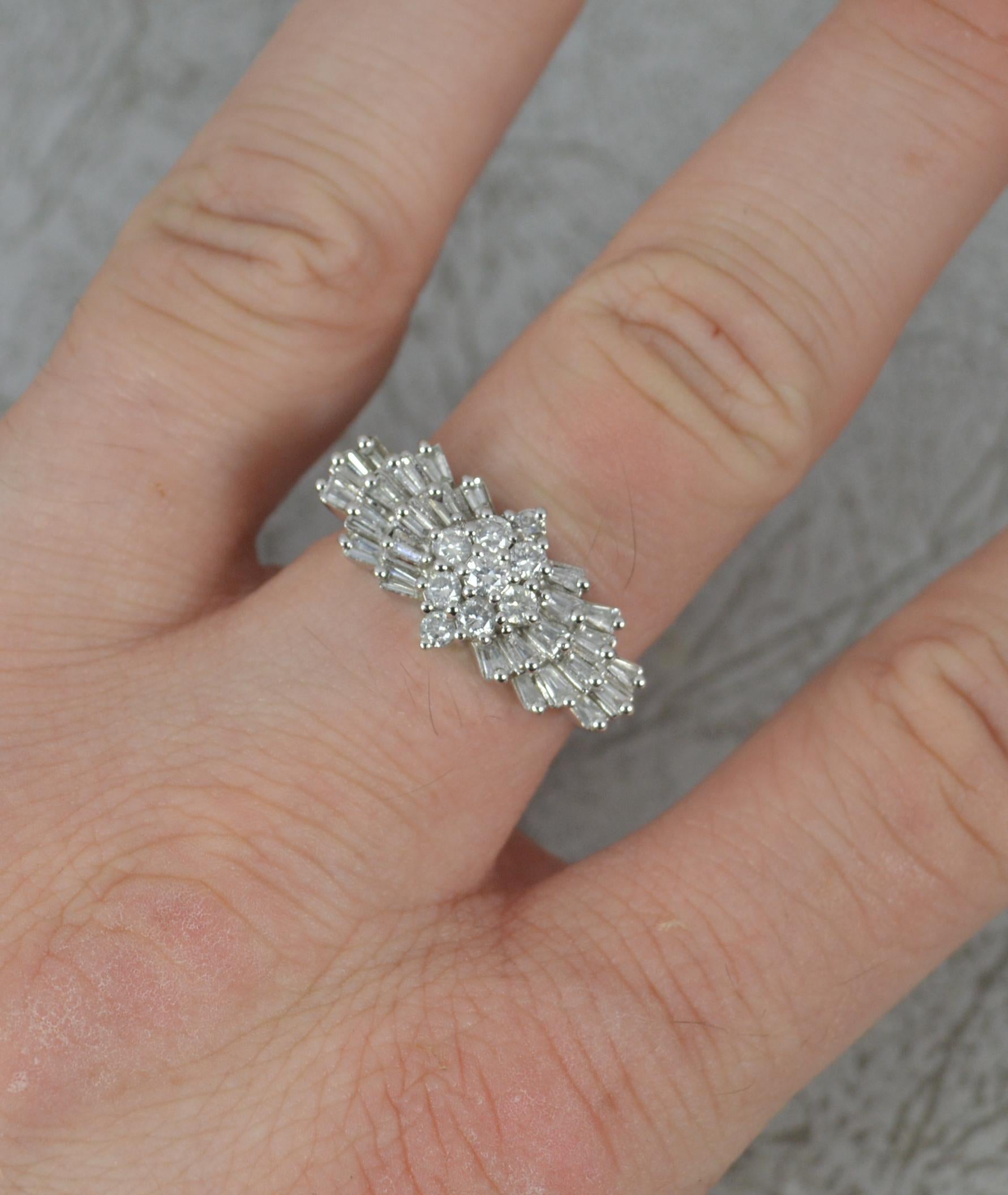 An impressive diamond cluster ring.
Solid 14 carat white gold shank and setting.
Designed with a diamond shaped cluster to centre of nine natural round brilliant cuts. Complete to each side with additional tapered baguette cut diamonds. 1.00 carat