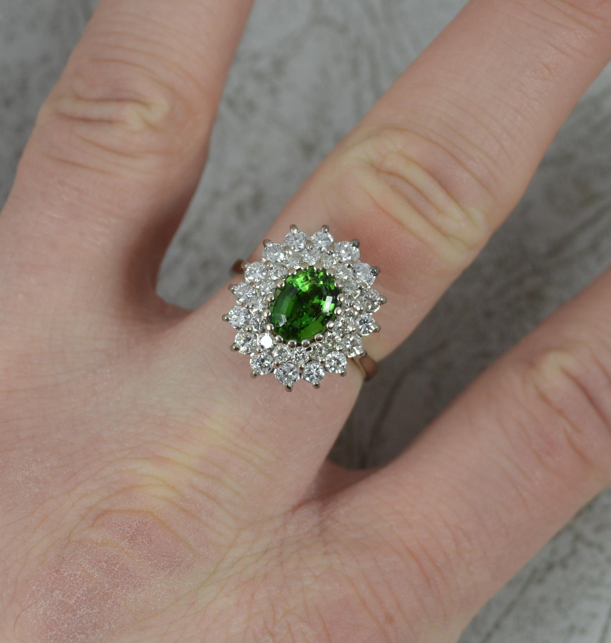 A superb contemporary cluster ring.
Solid 18 carat gold example. Well made substantial piece.
Designed with an oval cut green tourmaline to the centre. 6mm x 8mm. Surrounding are two tiers of round brilliant cut diamonds of two sizes. Total diamond