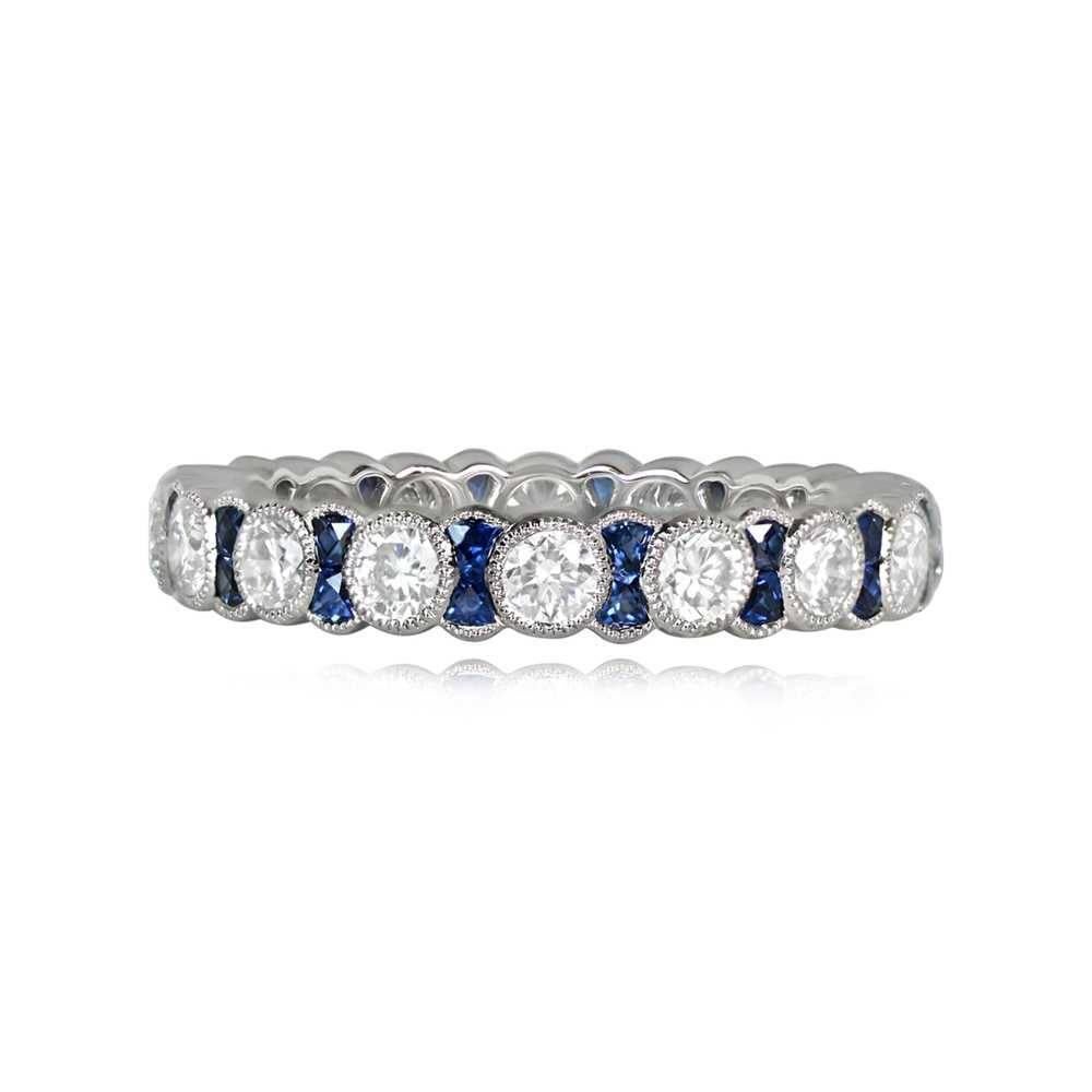 A stunning eternity band crafted in platinum, adorned with round brilliant-cut diamonds and calibre sapphires. The diamonds and sapphires are bezel-set and embellished with fine milgrain detailing. The band boasts approximately 1.00 carat of