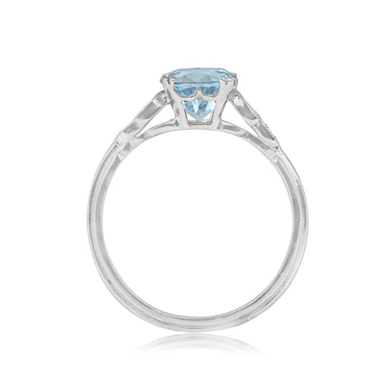 A charming gemstone engagement ring with an approximately 0.88-carat round-cut aquamarine nestled in prongs. The shoulders are adorned with a leaf motif, studded with old European cut diamonds. Crafted in platinum, the ring boasts a triple-wire
