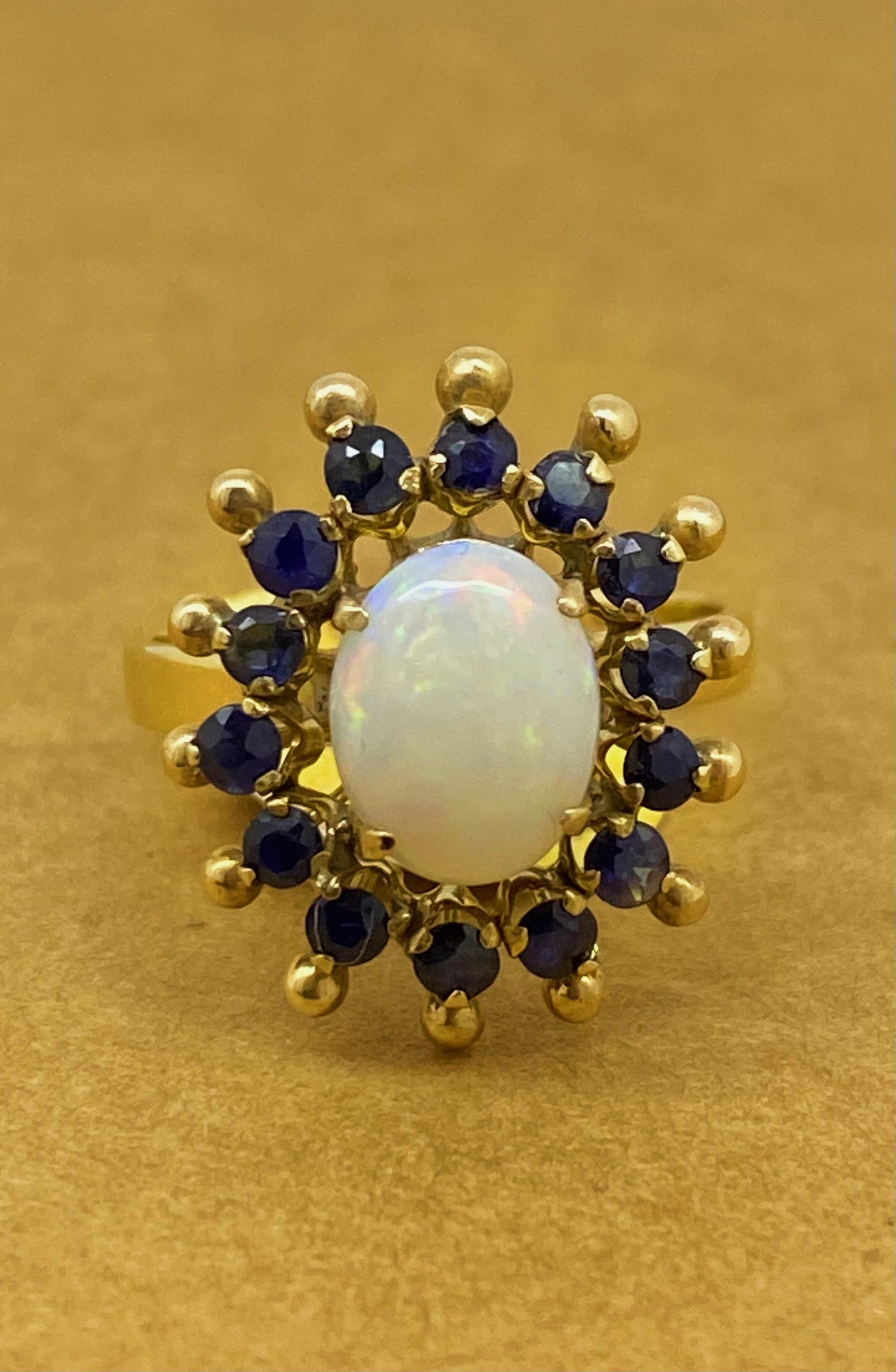 Con un delizioso design a forma di sole a doppia aureola, 
Questo anello vintage è caratterizzato da un'opale australiana solida. 
di forma ovale, misura 10 mm x 7,5 mm - 1,00ct circa. 
mostrando una bellissima miriade di colori

L'opale è