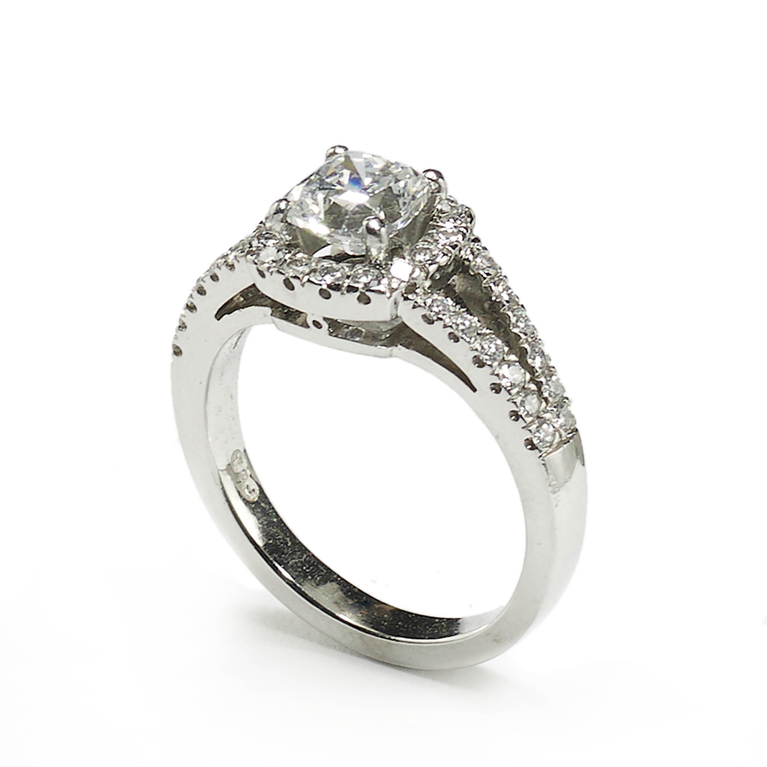A diamond solitaire ring, set with a 1.01ct, D colour, S11 clarity, cushion brilliant-cut diamond, in a four claw setting, with a round brilliant-cut diamond surround and diamond set split shoulders, mounted in platinum, with English Hallmarks for
