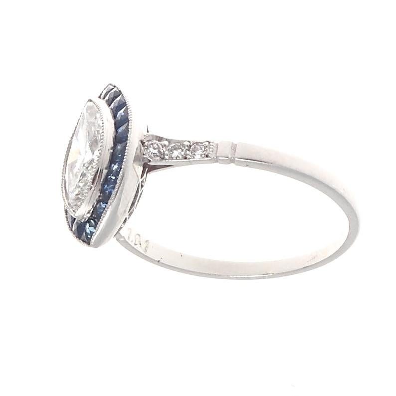 The perfect way to say I love you. Featuring a 1.01 carat marquise cut diamond that is approximately H color, SI2 clarity. Surrounded by perfectly calibrated navy blue natural sapphires to outline the diamond in a fascinating halo emphasizing the