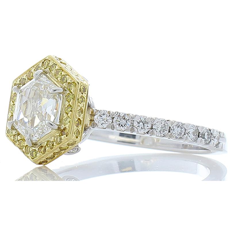The unique center diamond features an intriguing 1.01 carat fantasy cut hexagonal diamond. It is D color and VS clarity. The unique center diamond is surrounded by a beautiful halo of 0.30 carat of natural fancy vivid yellow diamonds, which decorate