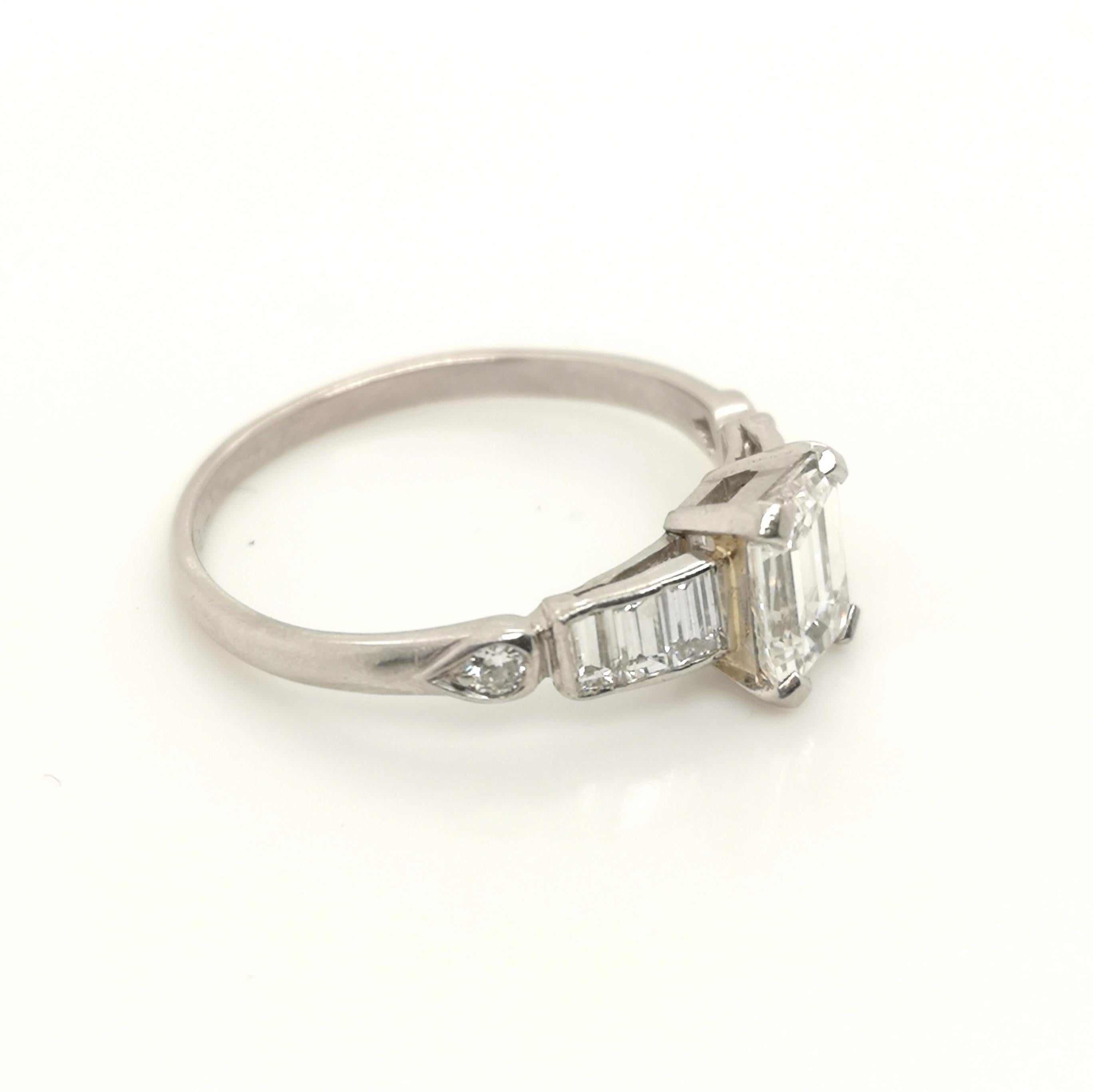 A platinum art deco ring mount, set with a new 1.01ct F VS1 emerald-cut diamond, accompanied by a GIA certificate, the shoulders are set with baguette-cut diamonds and with small round diamonds, in tear drop shaped settings at the ends, the