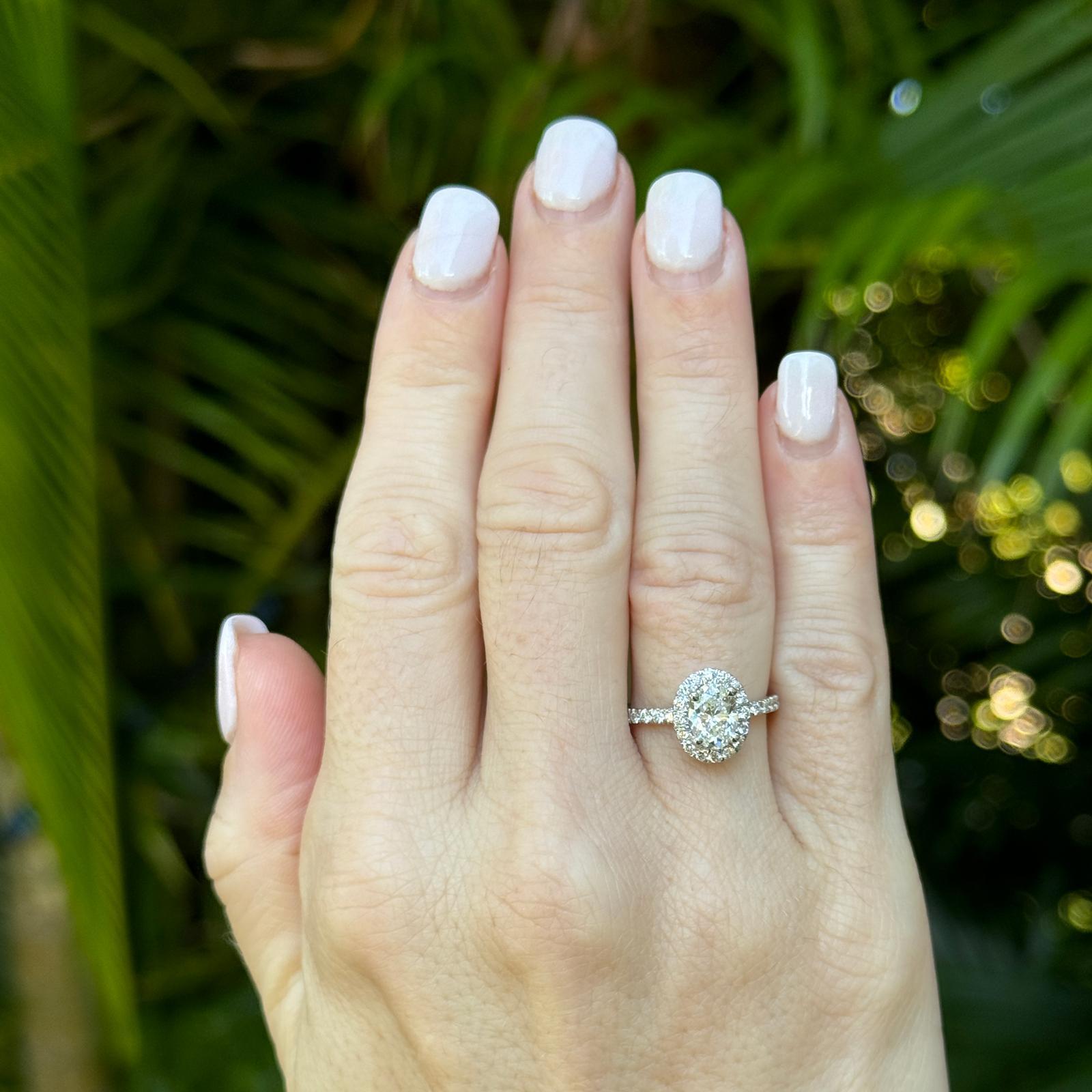 Oval diamond halo modern engagement ring crafted in 14 karat white gold. The ring features an 1.01 carat oval diamond set in halo mounting. The halo features 30 round brilliant cut diamonds weighing approximately .45 carat total weight. The diamonds