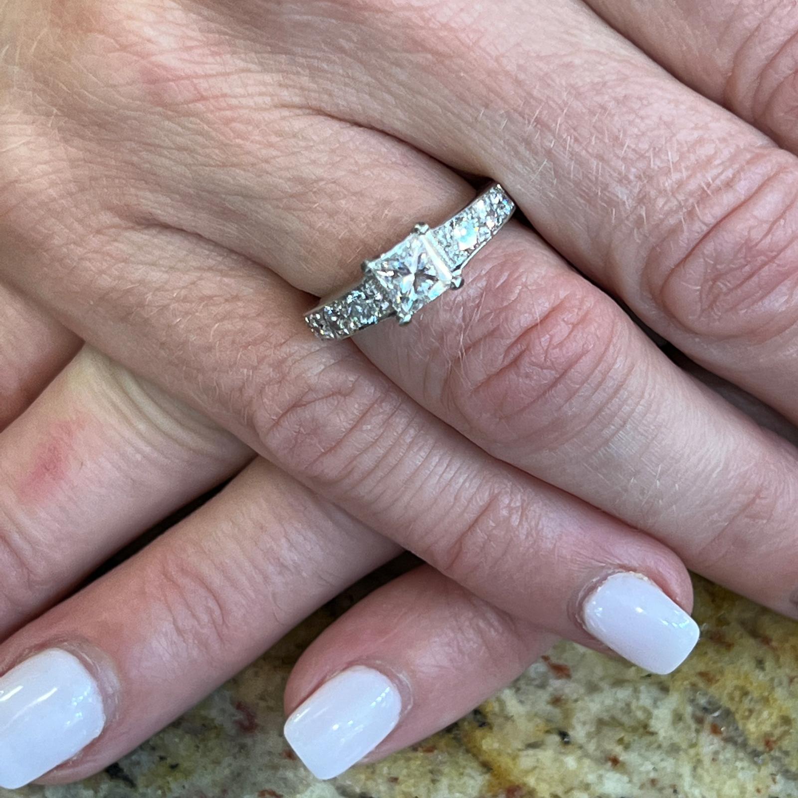 Anello di fidanzamento con diamante taglio principessa in oro bianco 14 carati. Il diamante taglio princess certificato GIA pesa 1,01 carati ed è classificato con colore E e purezza VVS2. I diamanti rotondi taglio brillante sono incastonati nella