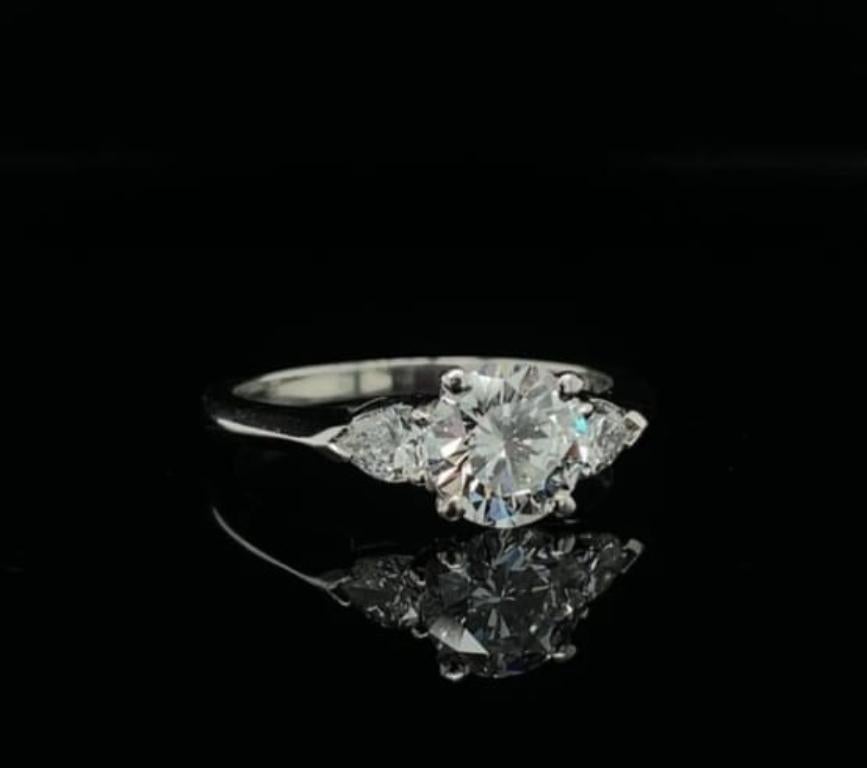 An elegant three stone diamond engagement ring set in platinum by Tiffany & Co

The ring is set to its centre with a 1.01 carat round brilliant cut diamond, estimated by ourselves as D colour, VS1 clarity. 
Pear brilliant cut diamonds of 0.14 carats