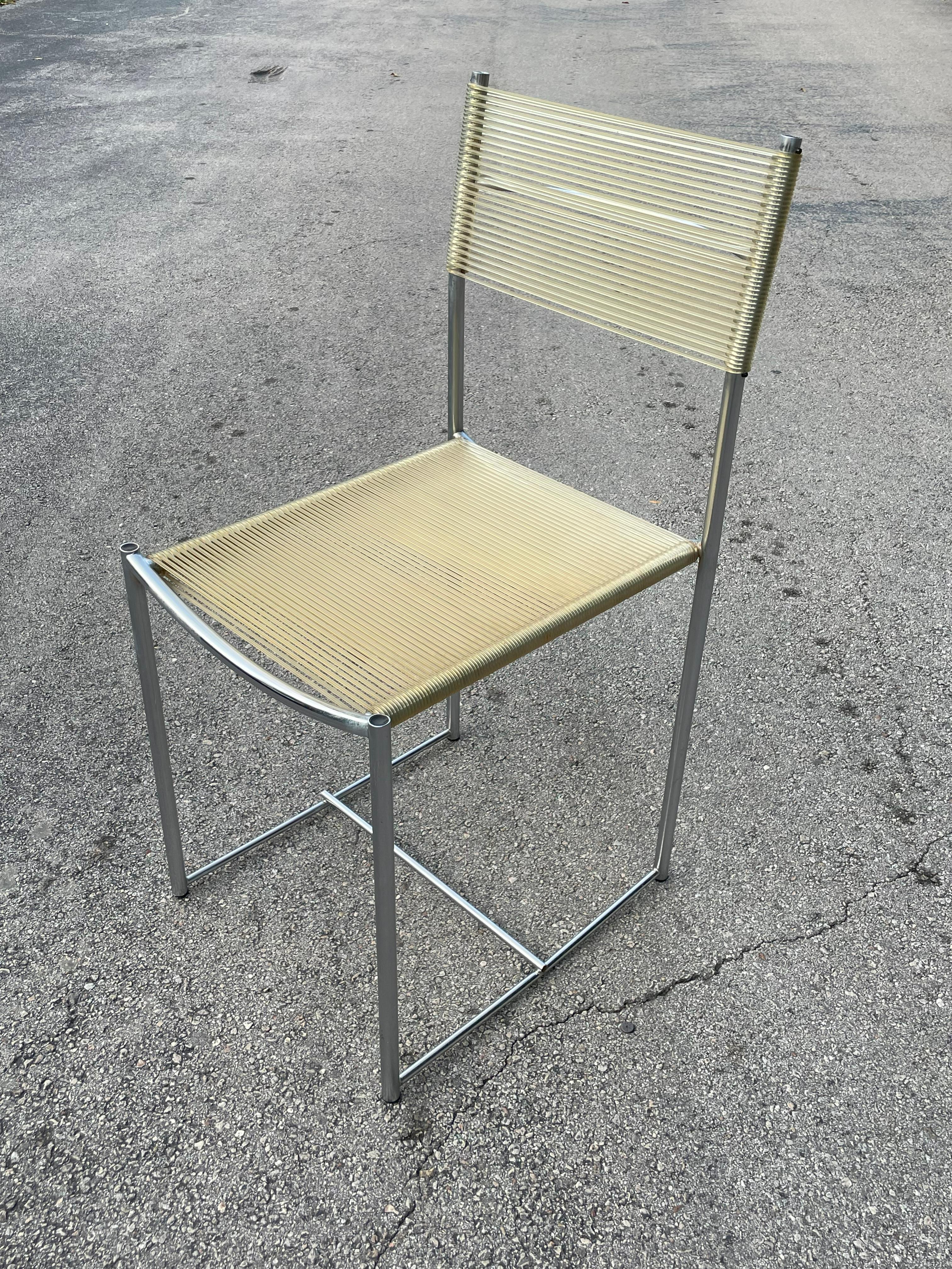 The Alias 101 Spaghetti Chair, designed by Giandomenico Belotti, features a sleek chromed or lacquered steel frame paired with a comfortable beige PVC seat and back. Belotti, who graduated from the University of Venice, had a diverse career in