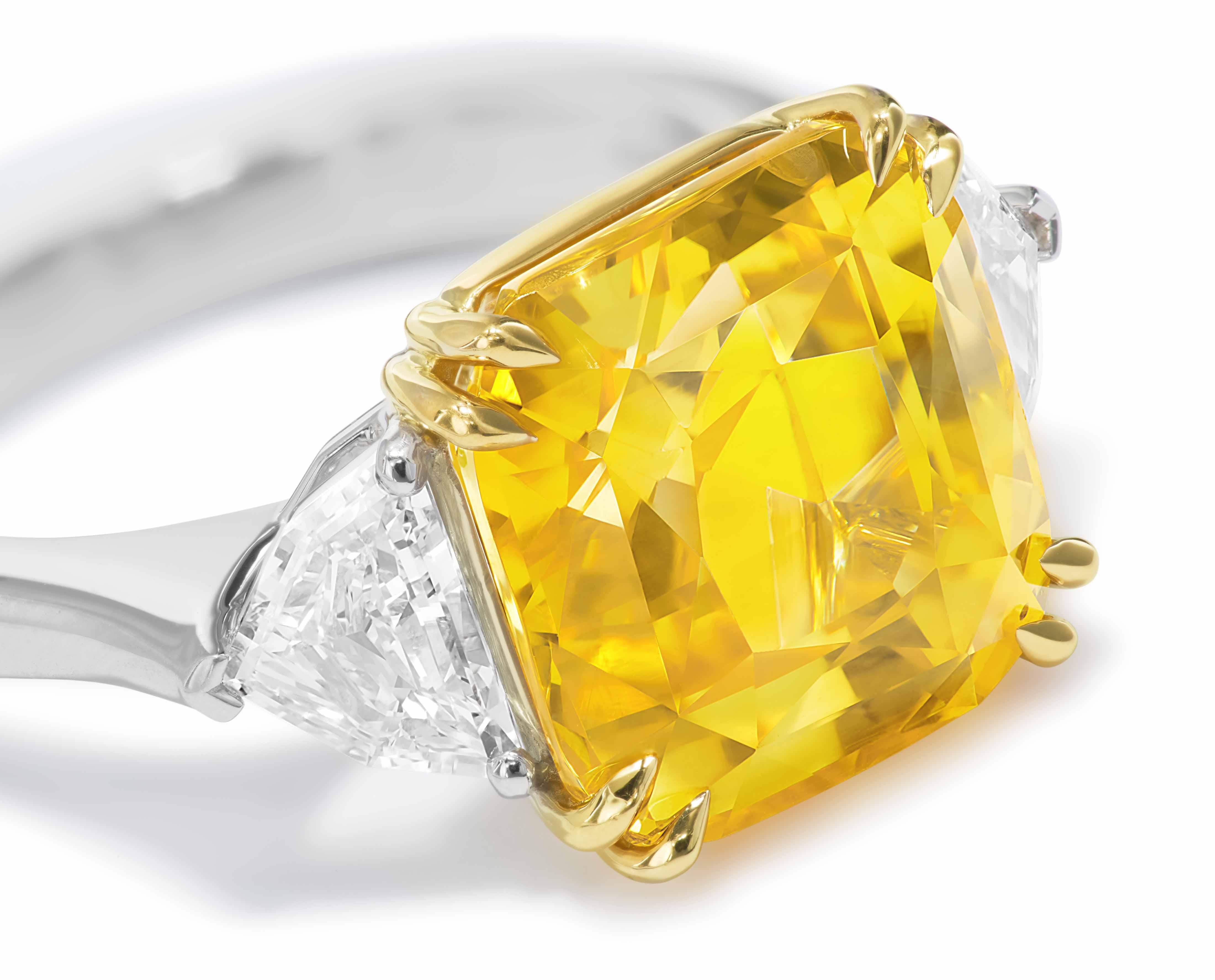 The main stone is a GIA certified 10.11 ct cushion-cut Yellow Sapphire from Sri Lanka. Side stones are GIA-certified collection-grade, epaulette-cut diamonds (0.50ct. D VVS1 and 0.51ct. E VVS1). The main stone is set in 18K yellow gold; the shank