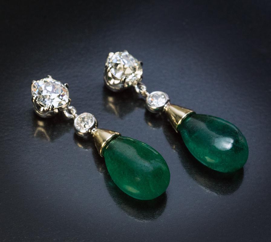 These contemorary yellow and white 14K gold post earrings feature two perfectly matched old mine cut drop-shaped Brazilian emeralds of an excellent alpine green color accented by four sparkling old European cut diamonds. 

The earrings are