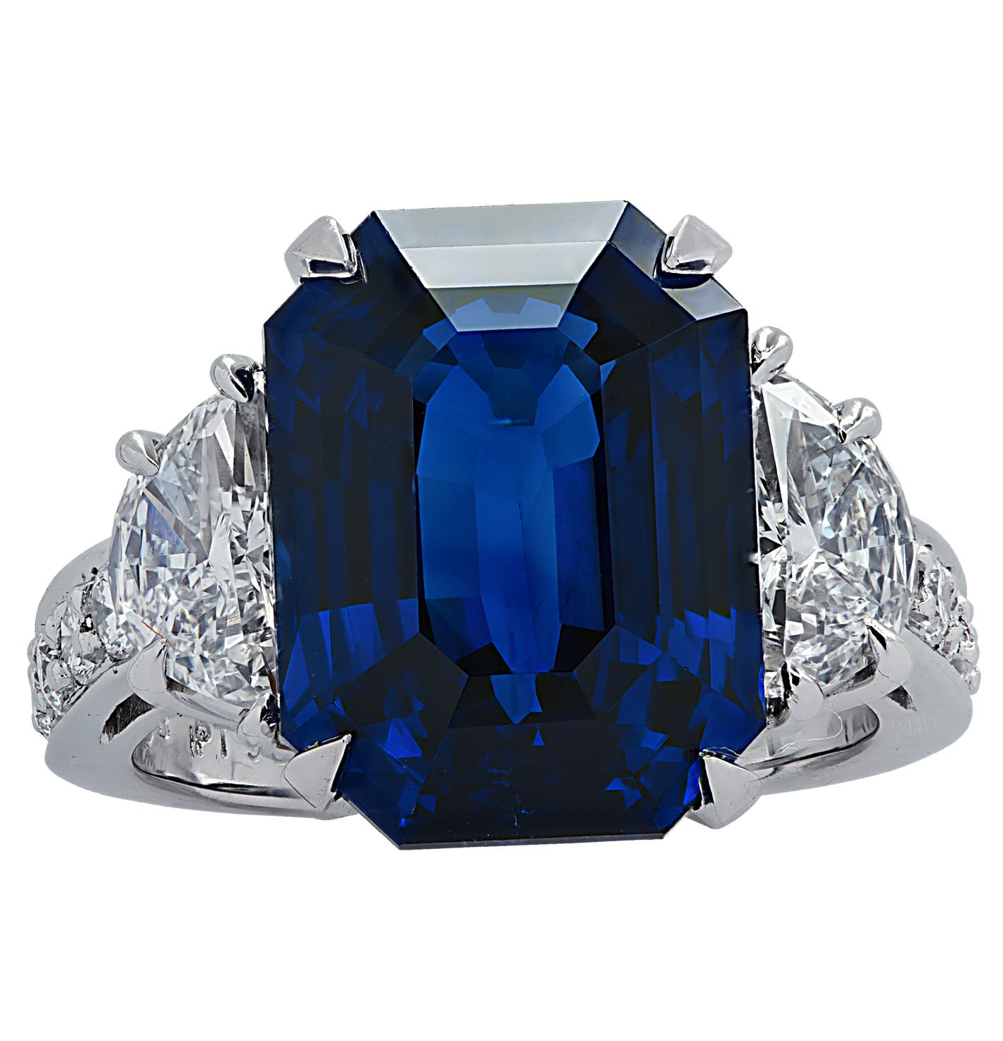 Stunning ring crafted in platinum, showcasing a spectacular emerald cut Sapphire weighing 10.17 carats total with two half moon diamonds weighing approximately .95 carats total G color, VS clarity, and 12 round brilliant cut diamonds weighing