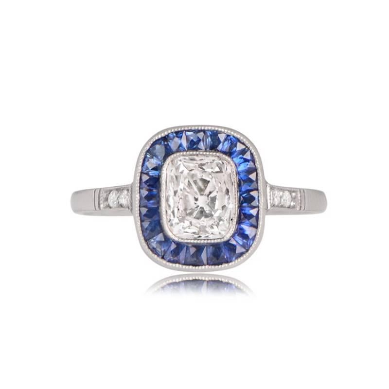 An exquisite halo engagement ring highlights an antique elongated cushion diamond, around 1.01 carat, displaying a captivating J color and VS2 clarity. The center diamond is encircled by a halo of natural French cut blue sapphires, with a collective