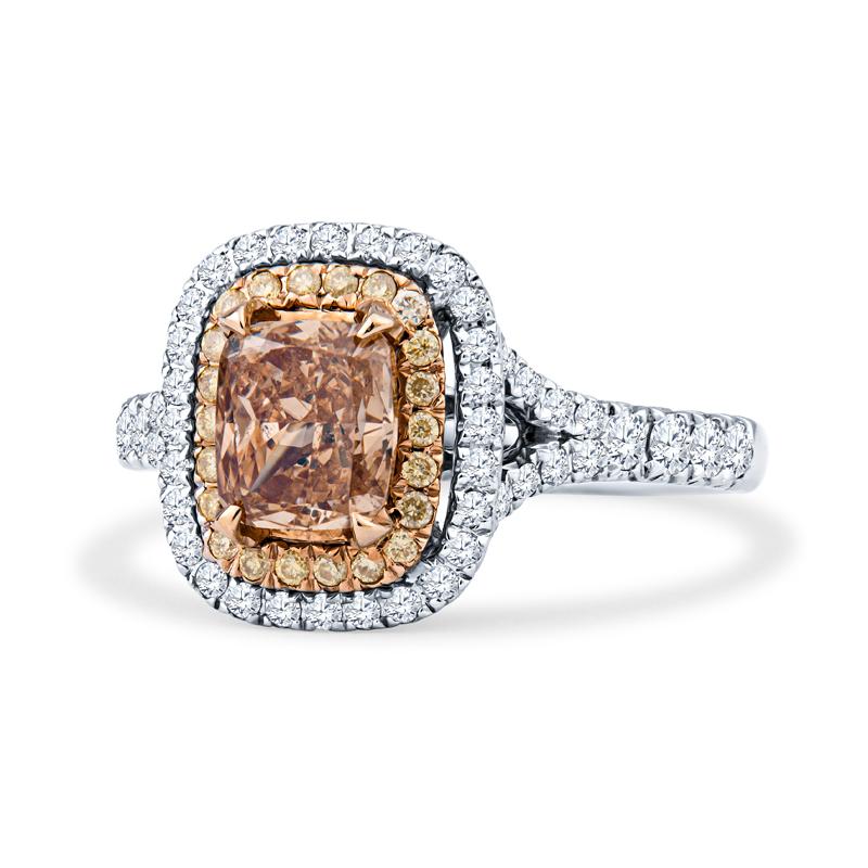 This engagement ring features a 1.01ct cushion cut natural fancy brown-orange center diamond, surrounded by 0.12ctw in yellow accent diamonds and 0.44ctw in white accent diamonds forming a double halo. The ring itself is 18kt white gold and yellow
