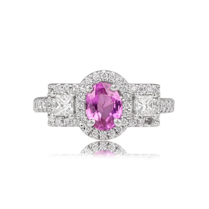 An elegant 18k white gold three-stone ring showcasing a 1.01-carat pink sapphire at the center, accompanied by two princess cut diamonds weighing a total of 0.69 carats. Each stone is securely set in prongs and encircled by halos of round