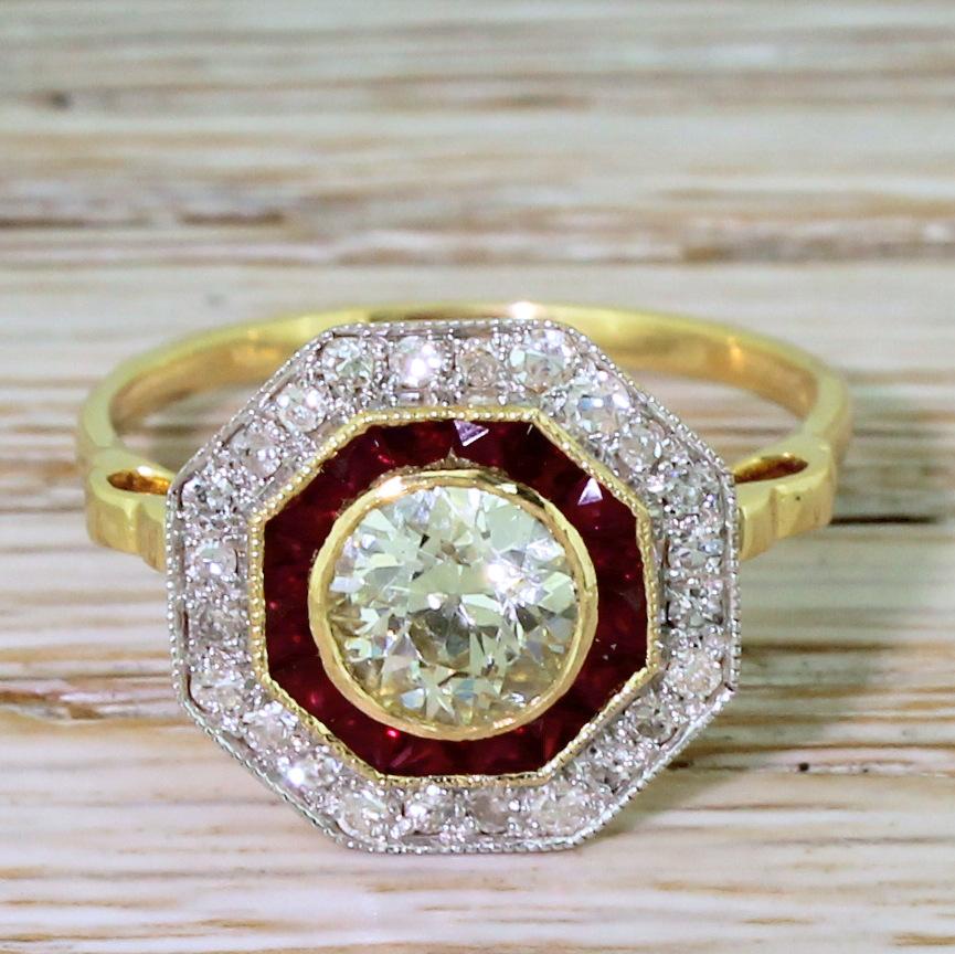A gorgeous diamond and synthetic ruby cluster ring. The rubover set old European cut diamond in the centre displays a distinct light yellow. Special-cut strong red synthetic rubies surround the centre stone, with a further halo of eight-cut diamonds