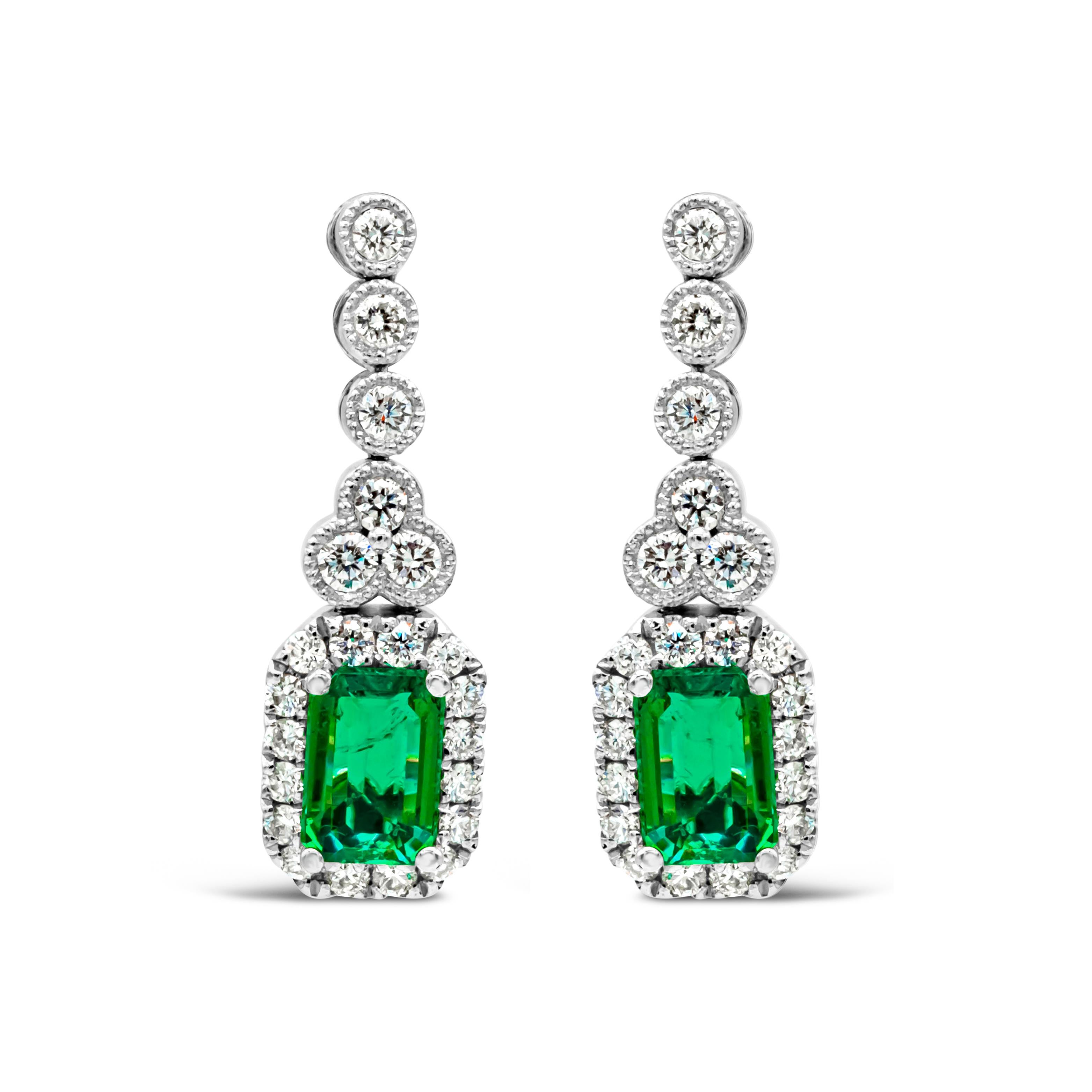 Each earring showcases a very fine emerald cut green emerald weighing 1.02 carats total, set in a classic four prong setting. Surrounded by a single row of round brilliant diamonds and suspended on a bezel set round diamonds weighing 0.52 carats