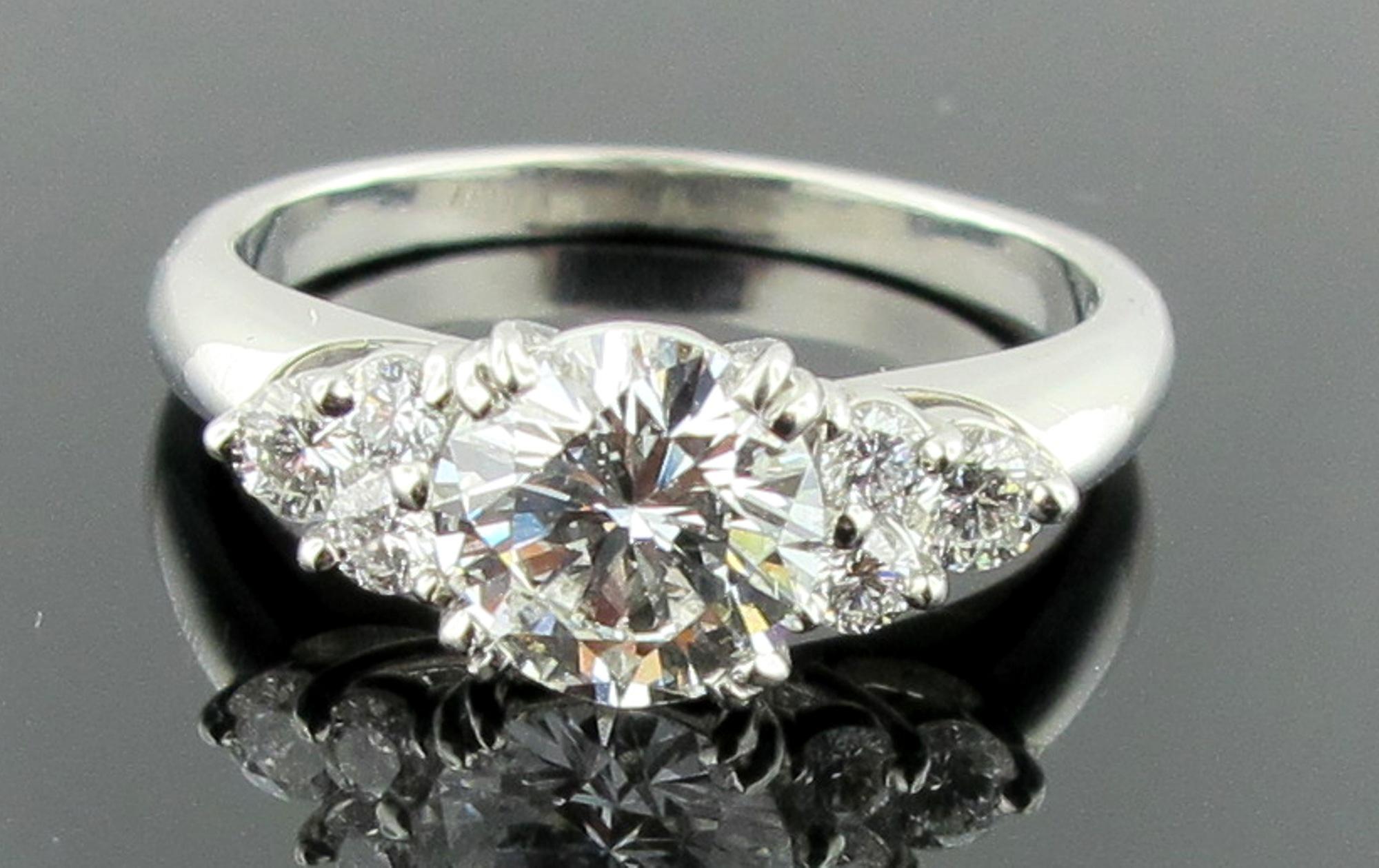 Set in Platinum is a 1.02 carat center round brilliant cut diamond, H Color, SI Clarity.  Along side are 6 round brilliant cut diamonds with a total weight of 0.25.  Total diamond weight is 1.27 carats.  Ring size is 6.