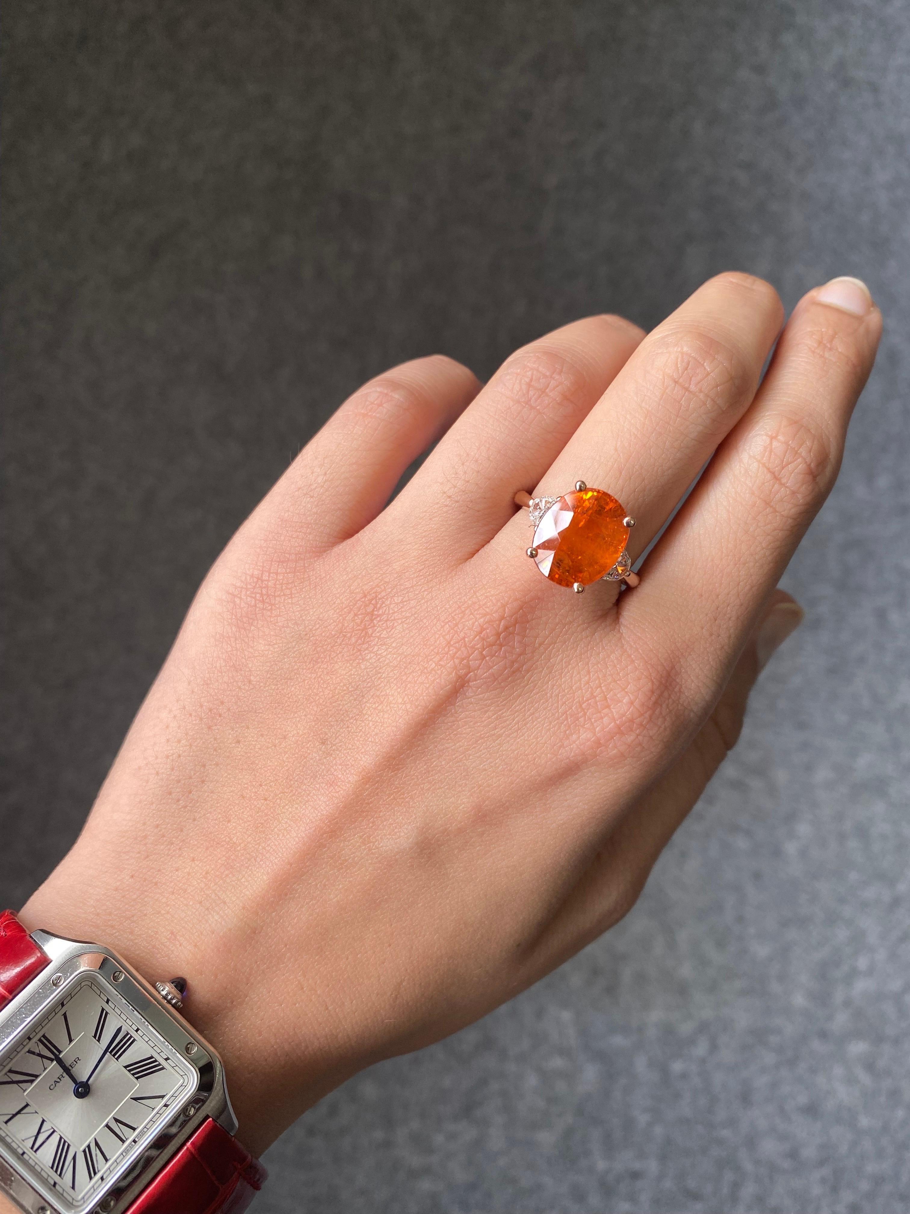 A classic three stone ring, with a 10.21 carat top oval cut Mandarin Garnet (Spessartine Garnet) centre stone and 2 half-moon 0.37 carat side stone White Diamonds. The ring is currently sized US 7, but can be resized. We provide free shipping, and