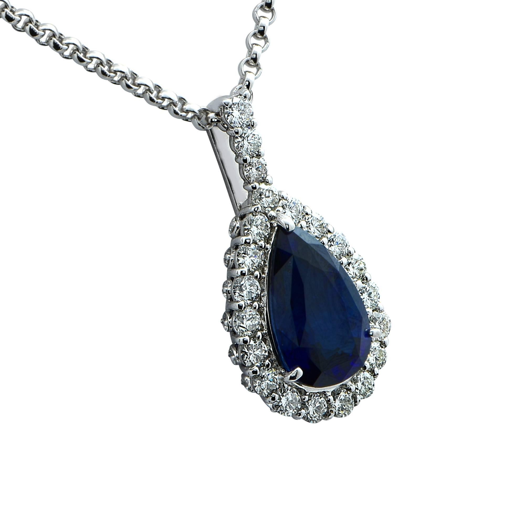Majestic rich blue pear shape sapphire weighing 10.23 carats, framed in 21 round brilliant cut diamonds, F color, VS quality set in 18 karat white gold, and suspended from a 16 inch 18 karat white gold rolo chain with a crab claw closure. The
