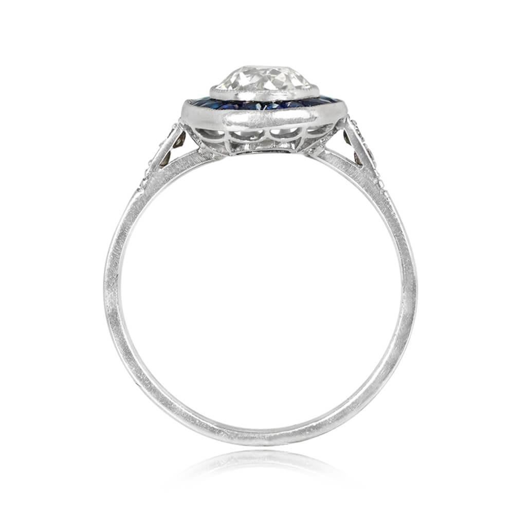 A captivating halo engagement ring featuring a bezel-set old European cut diamond at 1.02 carats, K color, and VS1 clarity. Encircling the center diamond are approximately 0.54 carats of French-cut sapphires. The shoulders are adorned with