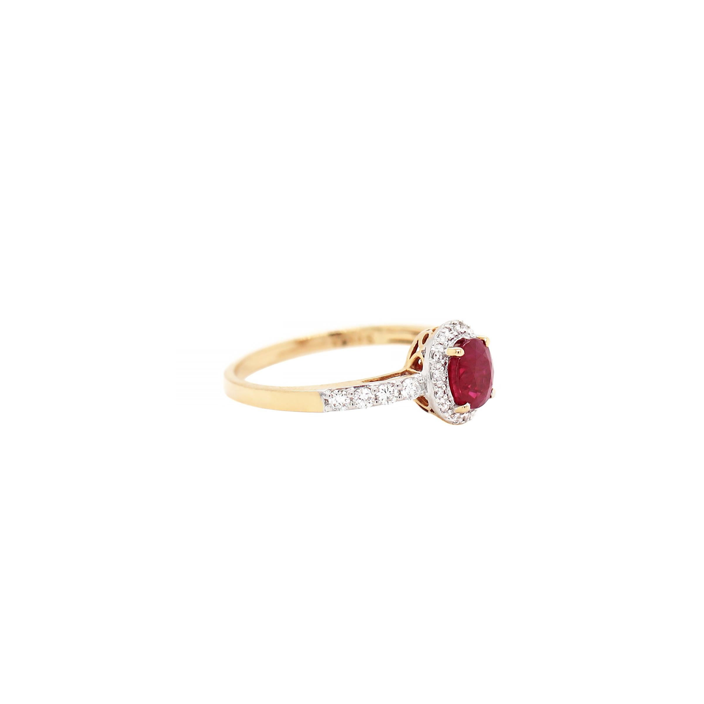 This beautiful ring features a vibrant oval shaped ruby weighing 1.02ct in a yellow gold four claw open back setting, surrounded by 24 fine quality round brilliant cut diamonds. The ring is further set with four round brilliant cut diamonds on