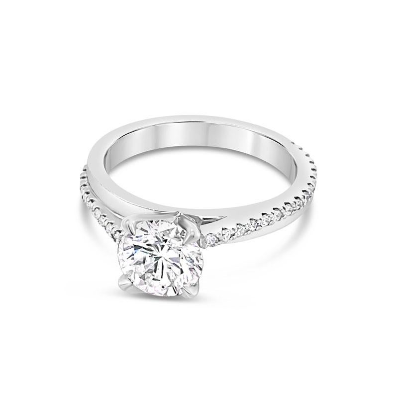 This unique engagement ring features a 1.02 carat round brilliant cut diamond of F SI1 quality and is set in 14 karat white gold with .20 carat total weight in round brilliant cut diamonds in a bypass style on the band. It is currently a size 4.75