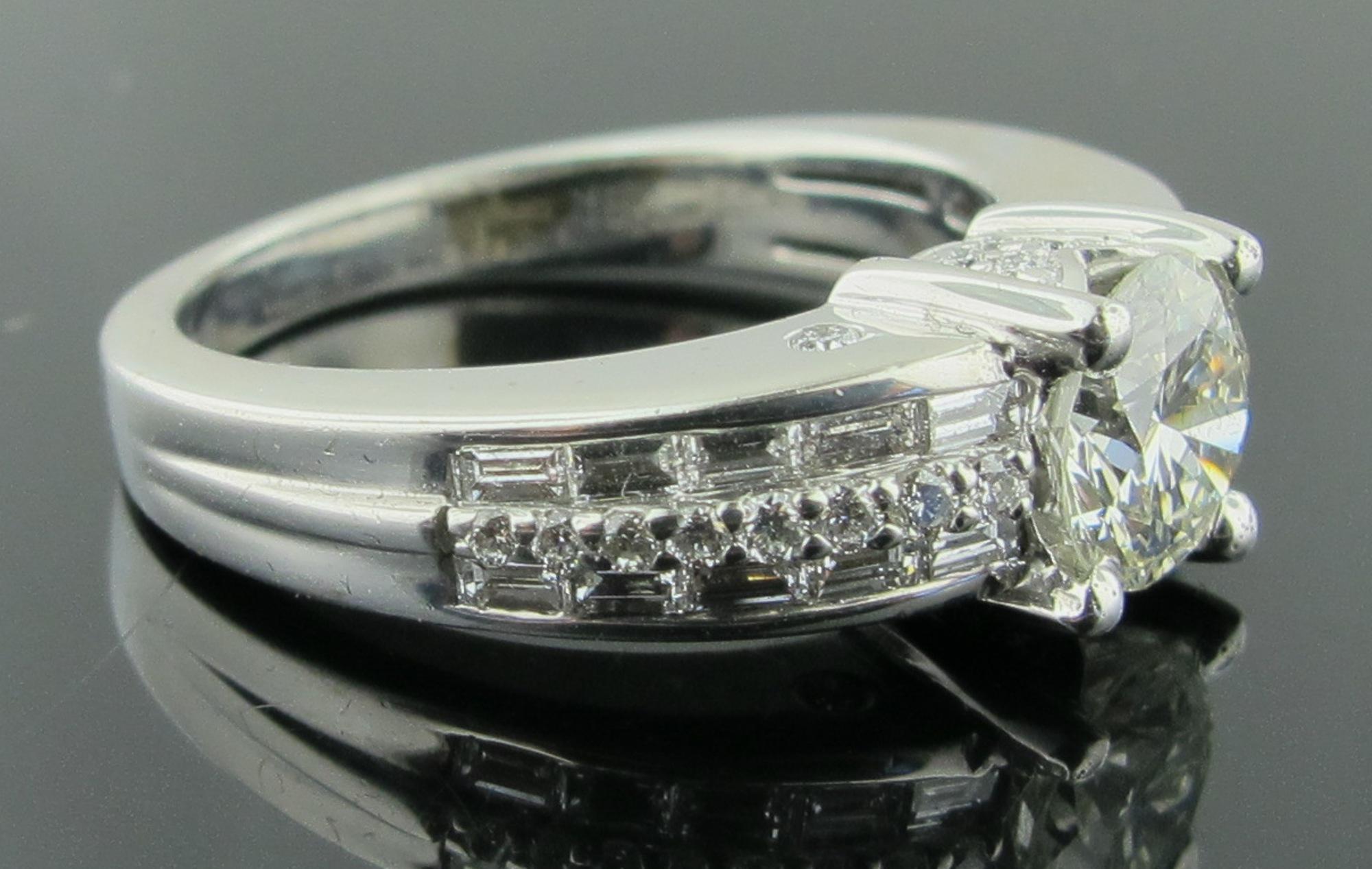 Set in 18 karat white gold is a 1.03 carat round brilliant cut diamond, Color J, Clarity VS.  In addition are 20 baguette cut diamonds, weighing 0.50 carats and 28 round brilliant cut diamonds weighing 0.25 carats, with a total diamond weight of