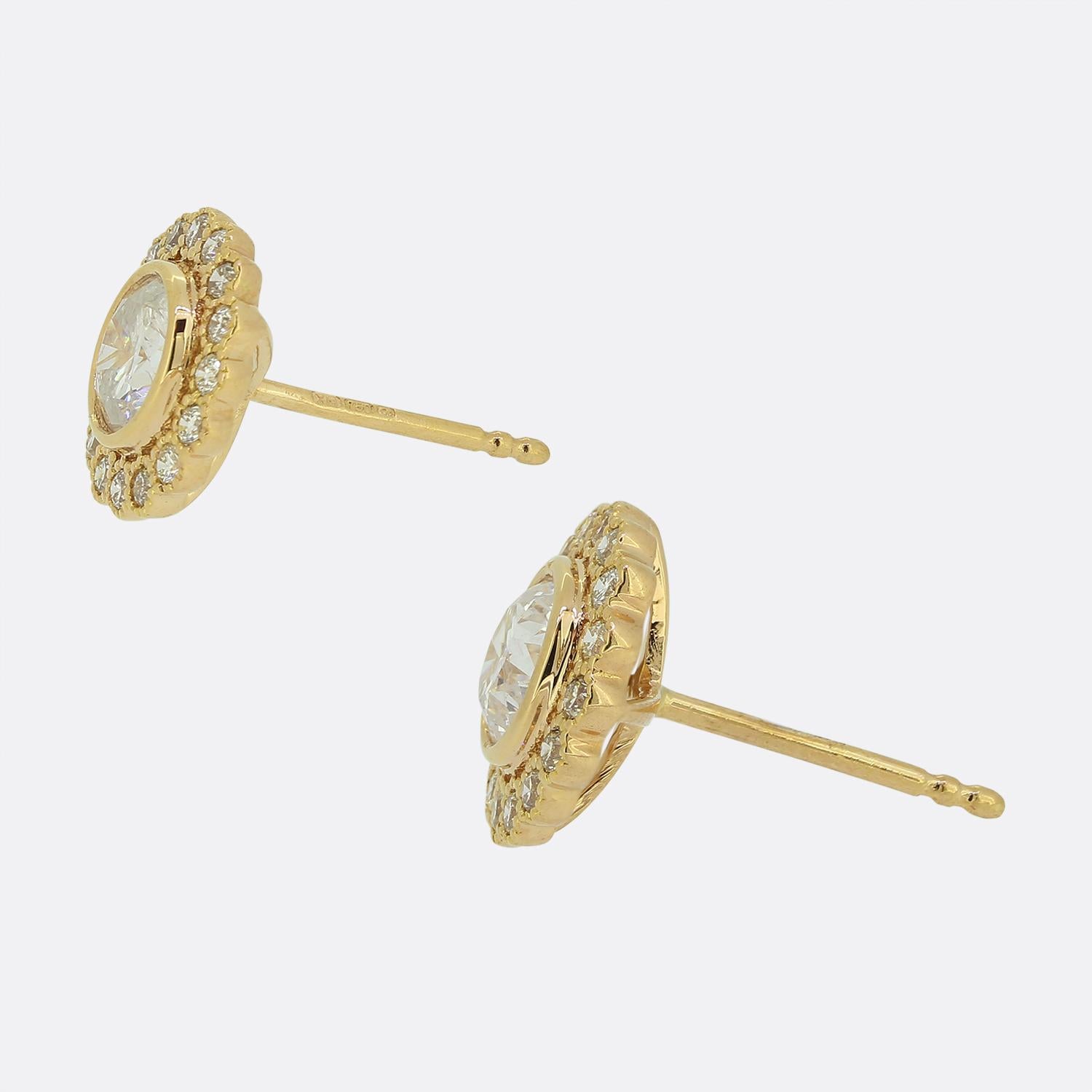 Ecco un affascinante paio di orecchini con diamanti in oro rosa 18 ct. Ogni pezzo ospita un singolo diamante rotondo taglio brillante da 0,52 carati in un'accurata montatura rub-over. Questa pietra centrale è circondata da un'aureola di 16 diamanti