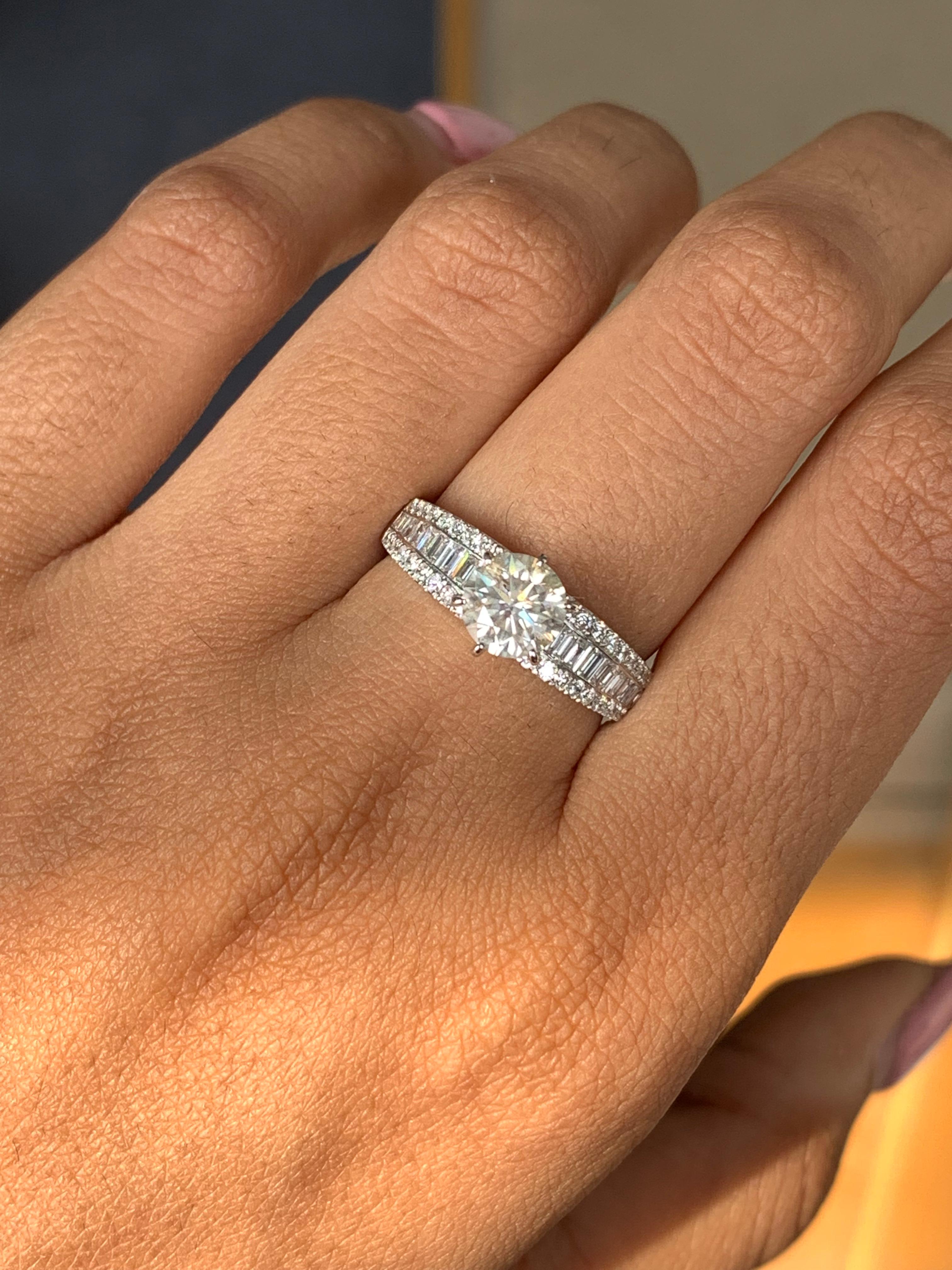 Es una creación impresionante, y el precio es igualmente atractivo. El anillo presenta un cautivador Solitario de Diamante Redondo de 1,03 quilates en su centro, engastado en una garra y acompañado de otros 0,60 quilates de diamantes laterales,