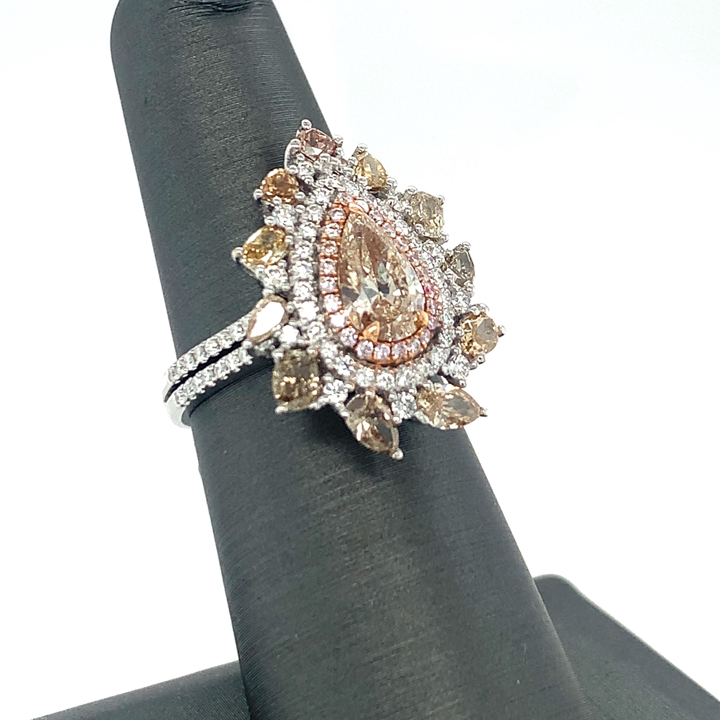 This Pear shaped champagne center diamond is surrounded by three layer halo of diamonds with half double line pave setting band. Innermost layer has pink, middle layer has white and outer layer has multi shaped & multi color diamonds. The unique