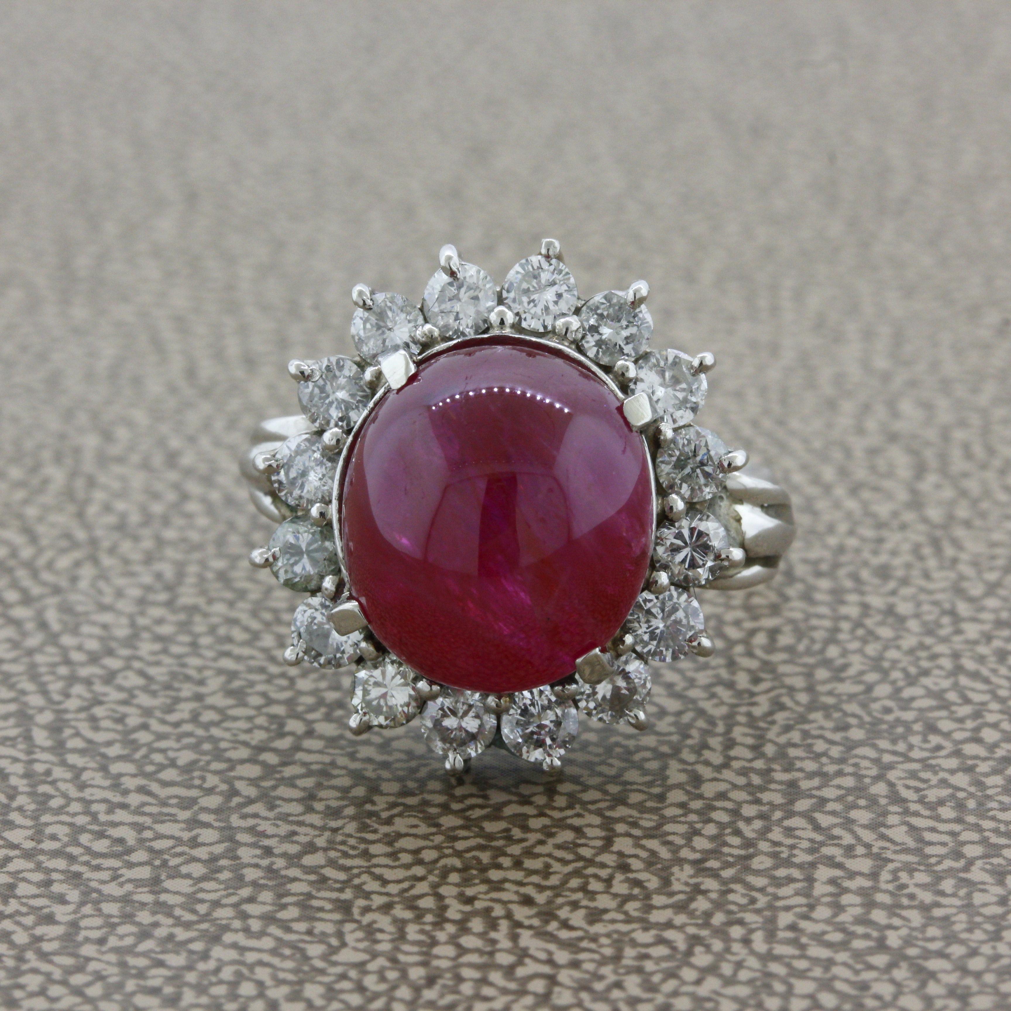 A large and impressive unheated ruby cabochon weighing 10.30 carats takes center stage. It has a rich pure red color along with great translucency making the stone appear to glow. It is complemented by a halo of round brilliant-cut diamonds weighing