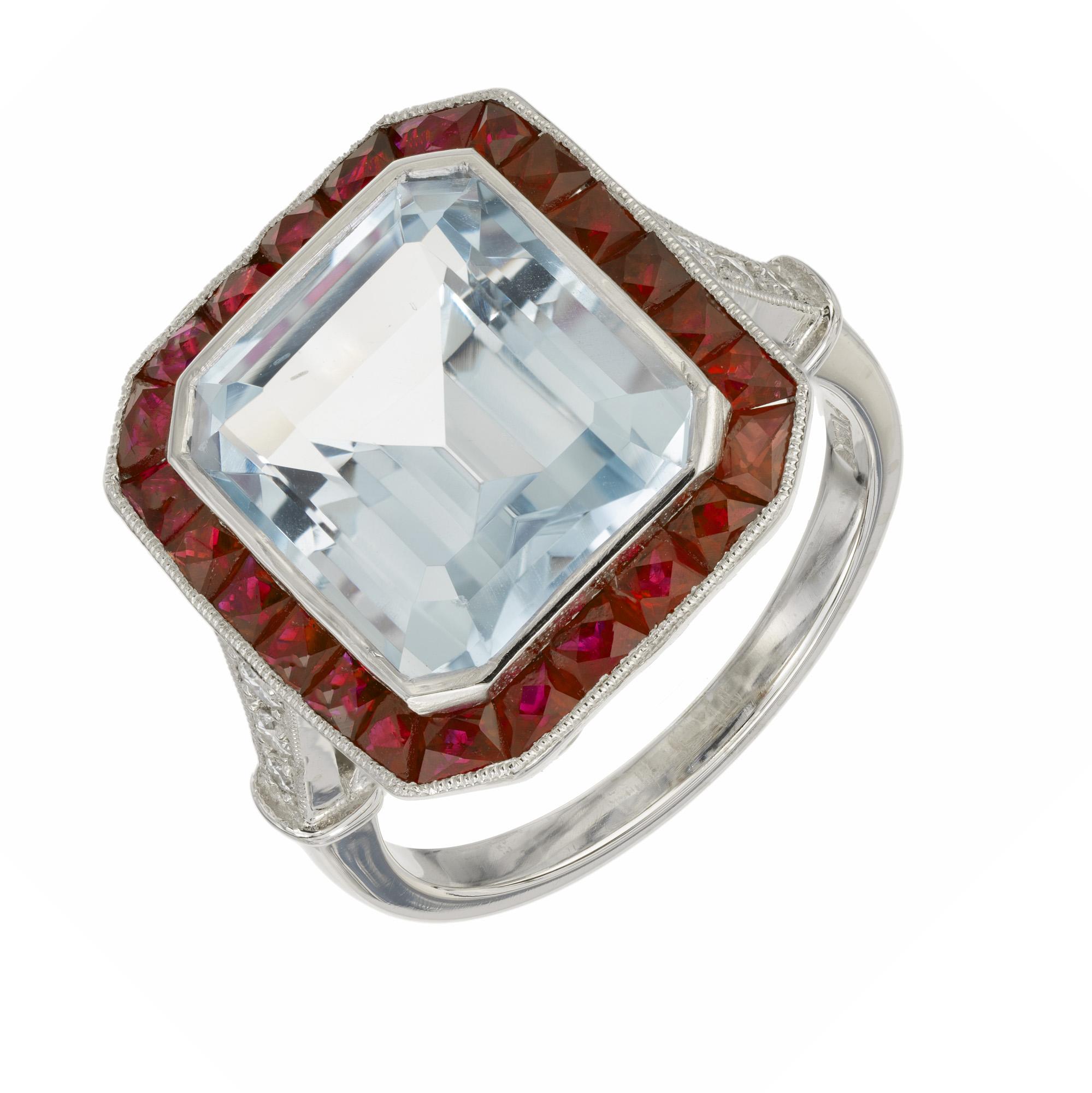 Magnificat 1930's Aqua, ruby and diamond engagement ring. At the center of this Art Deco design is a 10.35ct aquamarine mounted in a platinum setting with a halo of  French cut rubies and accented by 3 round brilliant cut diamonds on each shoulder.