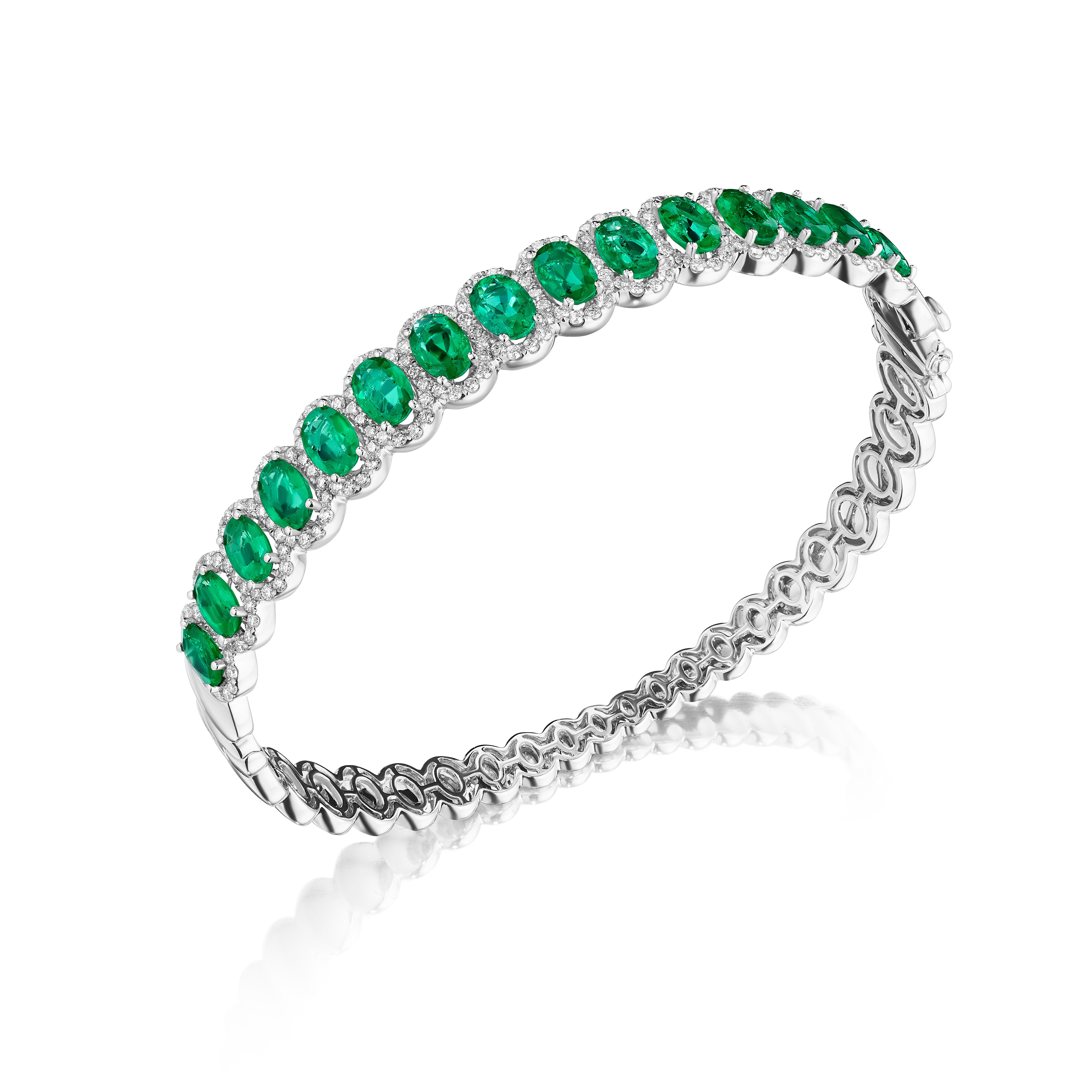 • A truly exquisite assortment of 15 oval cut green emeralds are framed by delicate halos made of round brilliant cut diamonds in this beautiful bangle. The stones are set in 14KT white gold and have a combining total weight of approximately 10.35