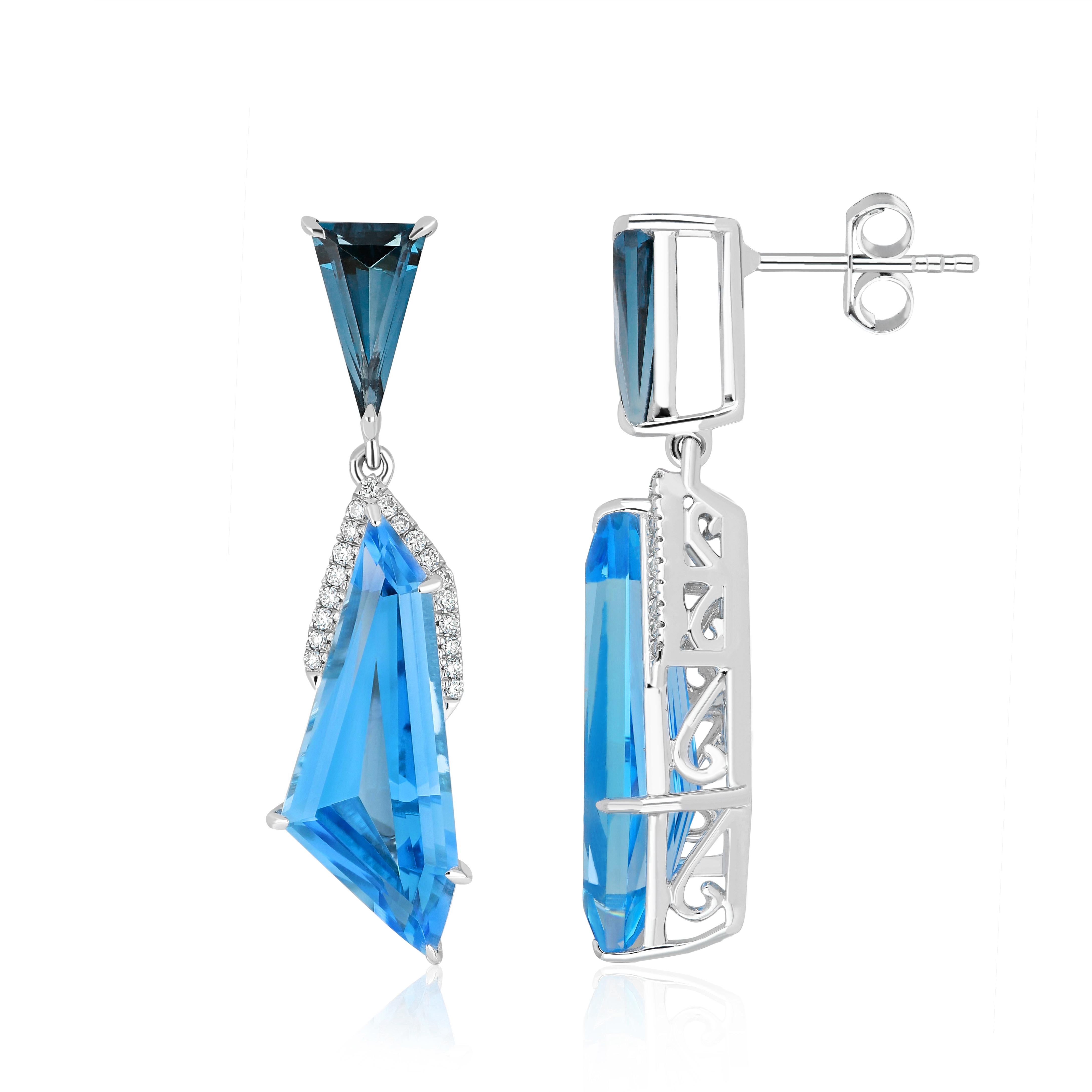 Découvrez un luxe intemporel : ces boucles d'oreilles exquises en or blanc 14 carats sont un mélange harmonieux de brillance et de sophistication. En son cœur, une époustouflante topaze bleue suisse de forme fantaisie taillée à facettes de 10,35cts