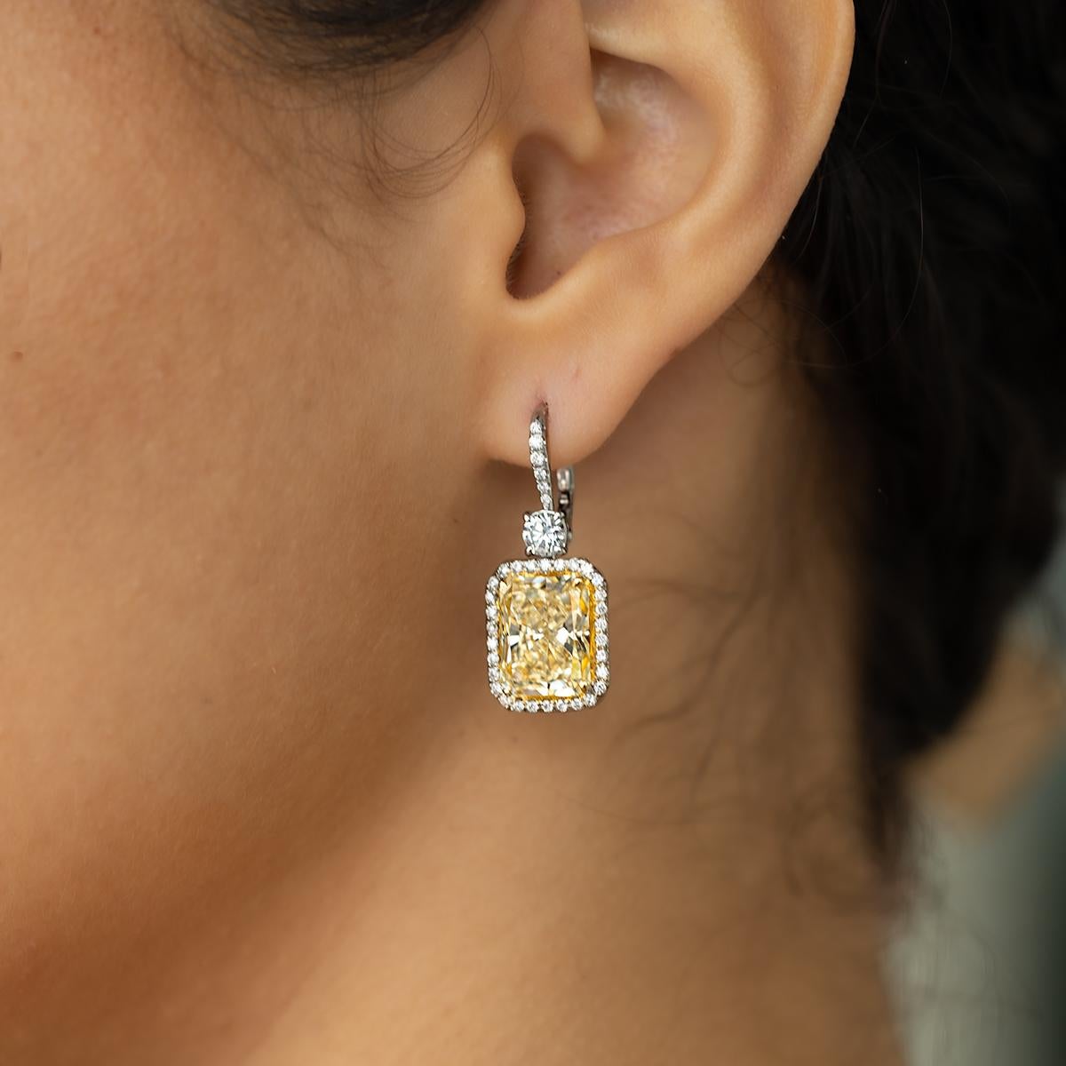 18k Earrings with 2 radiant cut light yellow diamonds weighing 10.36 carats and 1.19 carats of round white diamonds.