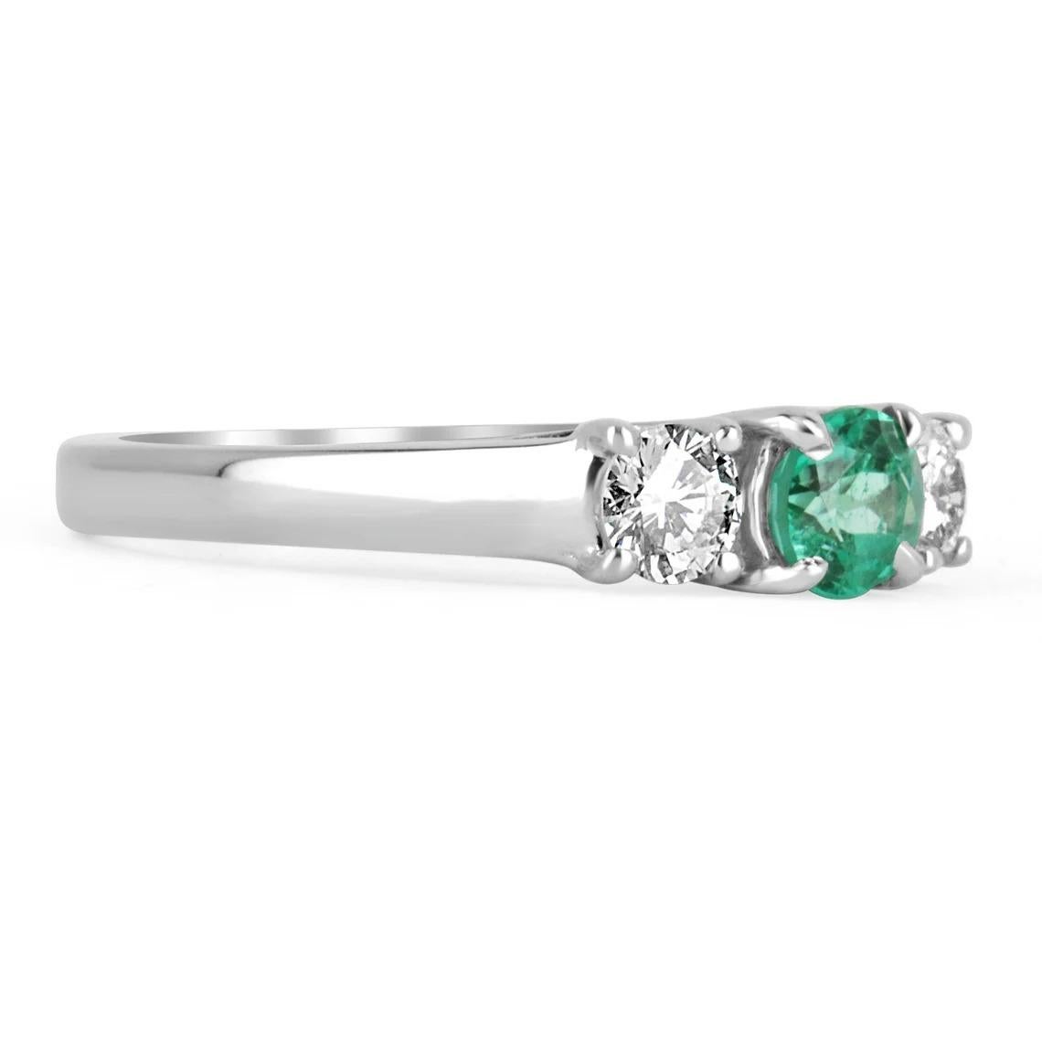 A classic, 14k solid gold natural emerald & diamond three stone engagement ring. A timeless engagement ring featuring a genuine round emerald flanked by two brilliant round diamonds. The Colombian emerald has very good qualities as it is mined from
