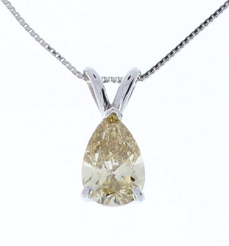 This impressive diamond solitaire pendant is finely crafted in brightly polished 14 karat white gold and features a pear shaped 1.04 carat diamond that has VS2 clarity, gracefully prong set on a shiny split bail. A sturdy box chain is threaded