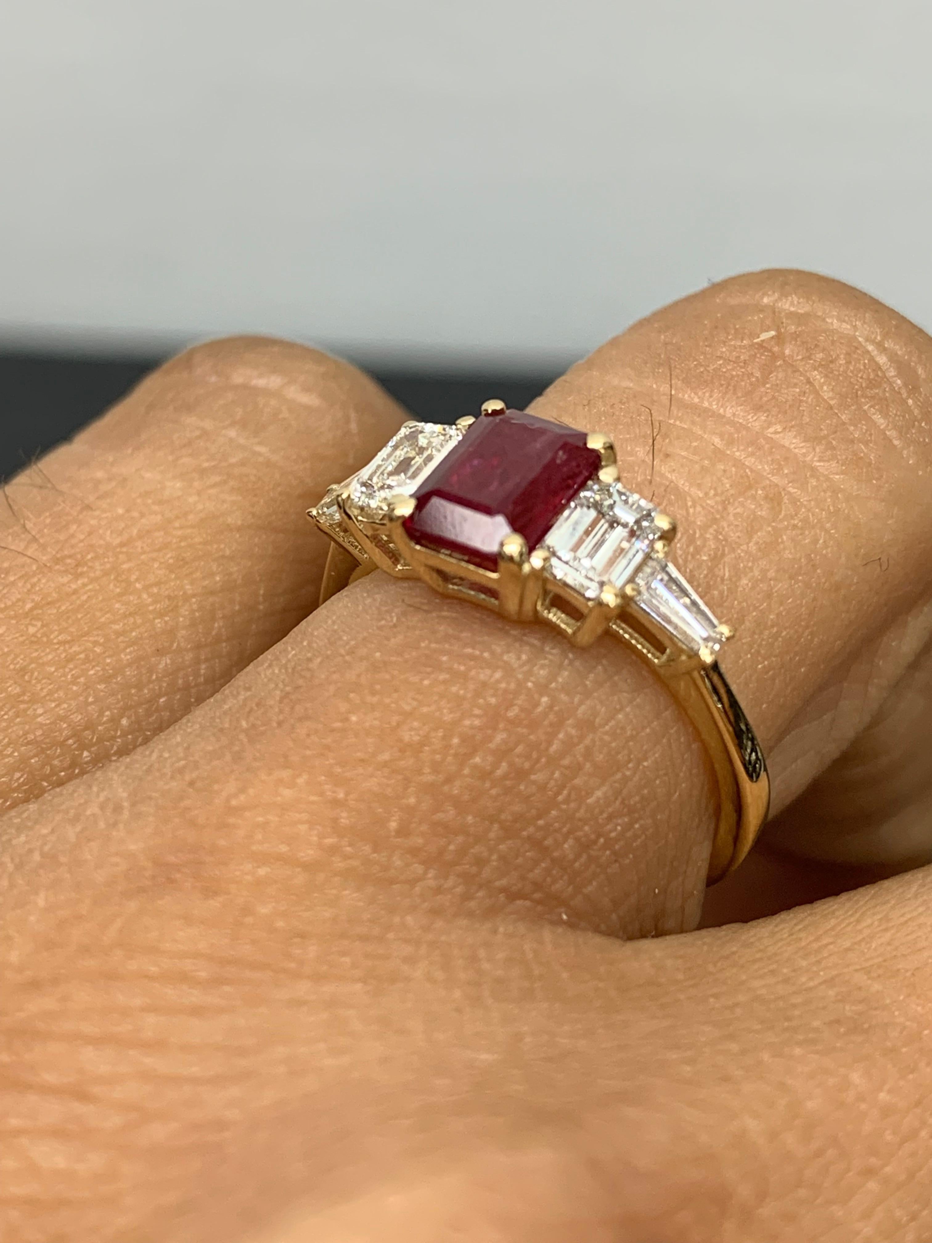 A stunning ring showcasing a rich intense emerald cut vivid red ruby weighing 1.04 carats.  Flanking the center stone are two emerald-cut diamonds weighing 0.64 carats and two baguette diamonds on each side weighing 0.21 carats in total, Made in 14K