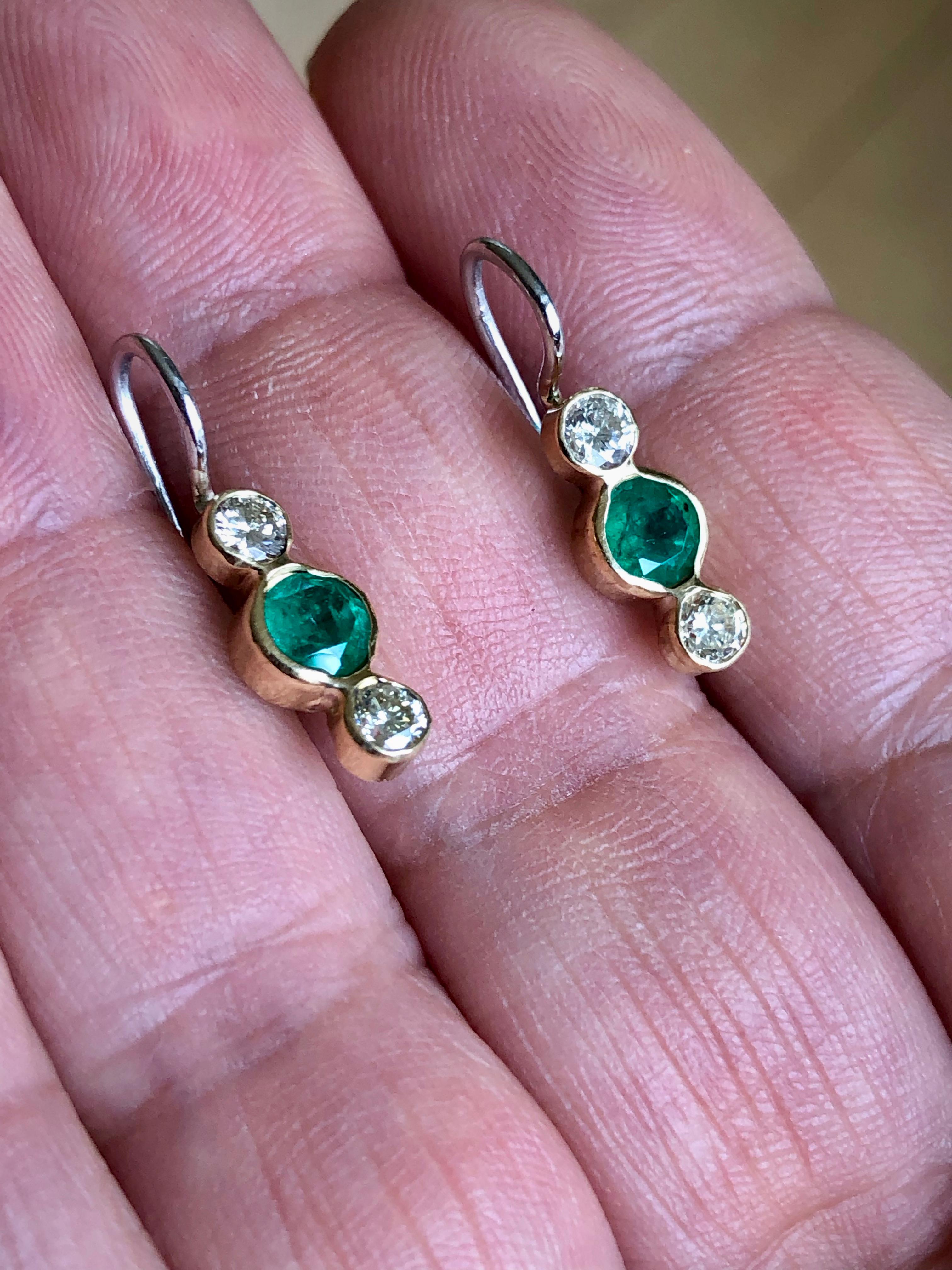 Delicate 18 karat yellow gold and platinum dangle drop earrings, features four round brilliant cut diamonds weighing .44cts L-VS, and two round cut natural Colombian emeralds weighing .60cts.  A feminine and elegant earrings which can be worn for