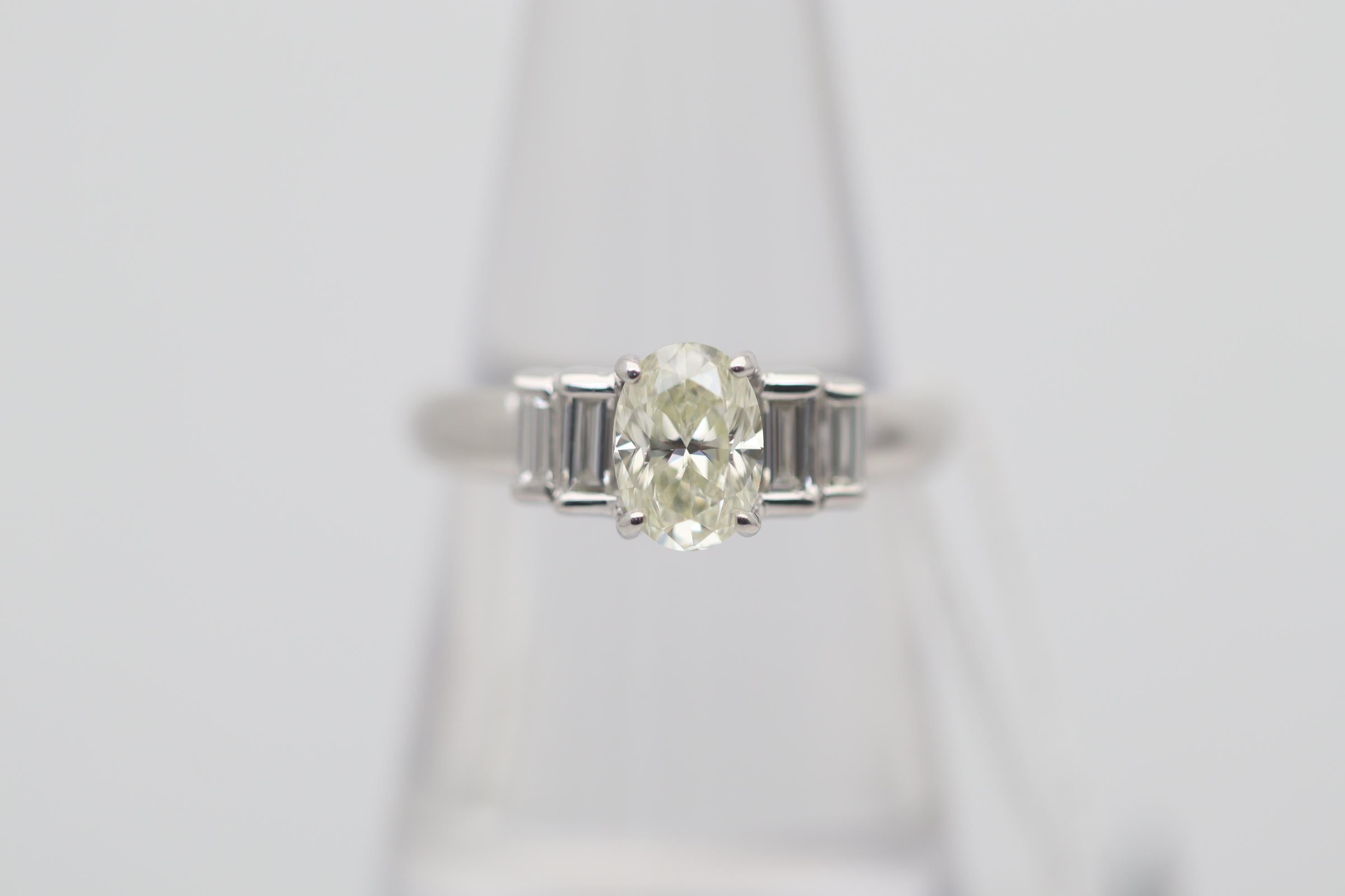 A classic and stylish engagement ring featuring a 1.04 carat oval-shape diamonds. It has a fancy very light- yellow color along with great clarity, VS2, making the stone eye clean with no visible inclusions. It is complemented by 4 baguette-cut