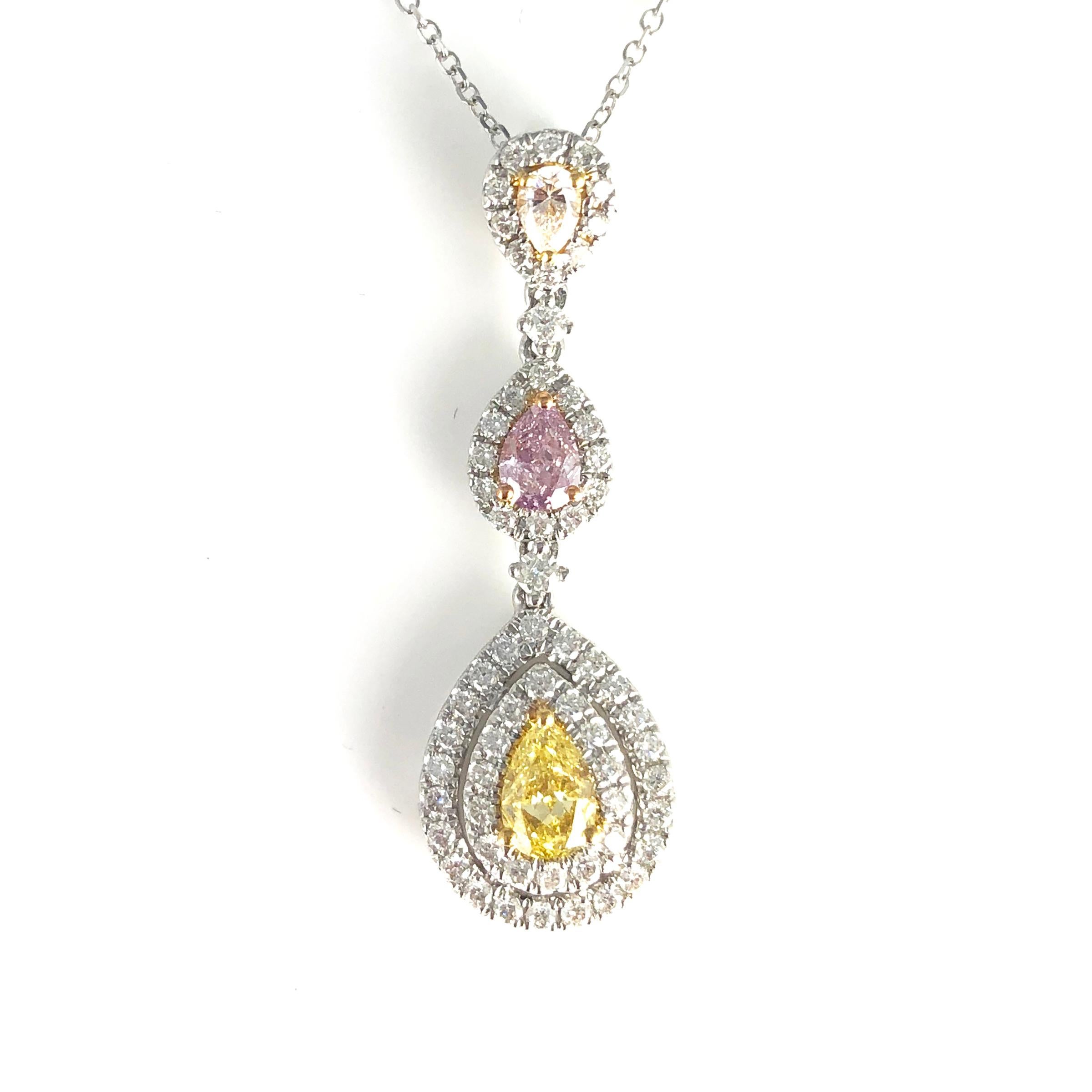 This stunning pendant features three pear shape natural color diamonds, arranged in three tiers, and surrounded by halos of round white diamonds.

The larger stone is a 0.31 carat GIA Certified Natural Fancy Orange Yellow diamond.
The second tier is