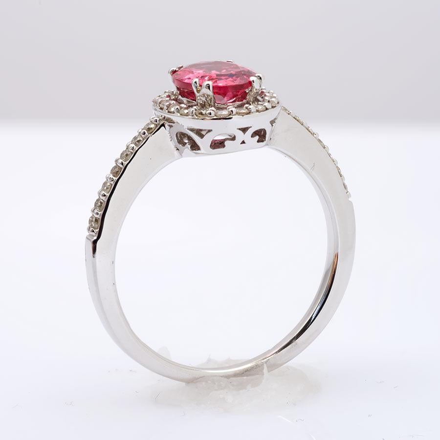 Double prongs fabricated in 14K white gold secure this electric Spinel in place. Its deep vibrant orangy rose pink color is lifted by the glitter the diamonds bring to the ring. Mined in Tanzania this rare neon colored spinel weighs 1.04 carats and