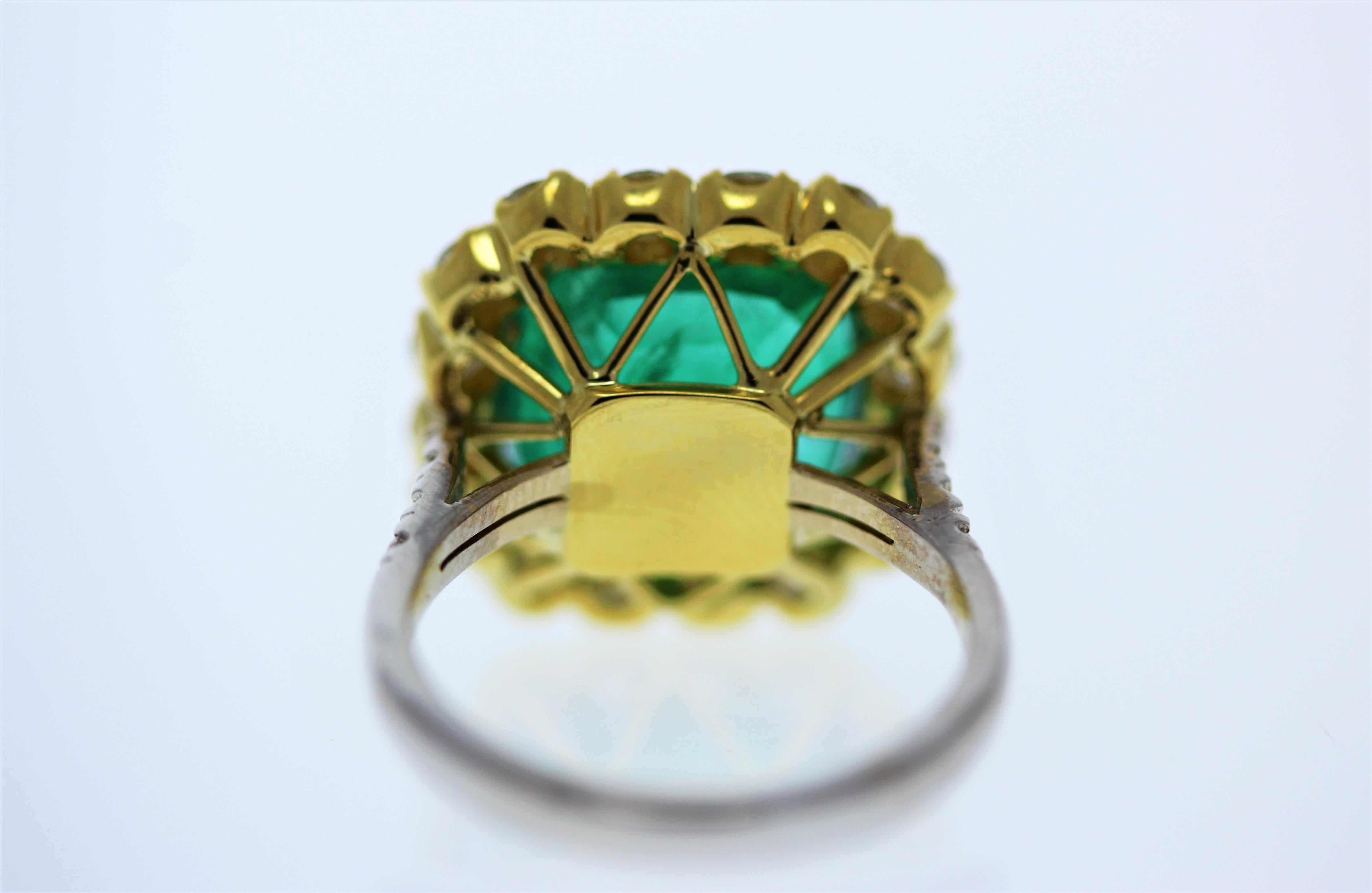 This ring features a spectacular 10.41 carats cushion cut emerald. Its origin is Zambia, its color is bright grass green. In addition to its size, the transparency and clarity make this gem sought after. The sparkle from the emerald is enhanced by a