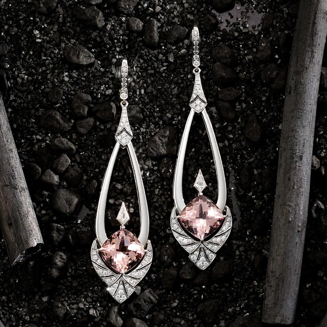 These beautiful Matthew Ely 18ct white gold earrings feature  2 = 10.43ct Cushion cut Morganites, with art deco inspired chandelier drops set with 2 = 0.16ct kite shaped diamonds with an additional 0.74ct of fine white diamonds in the detail of this