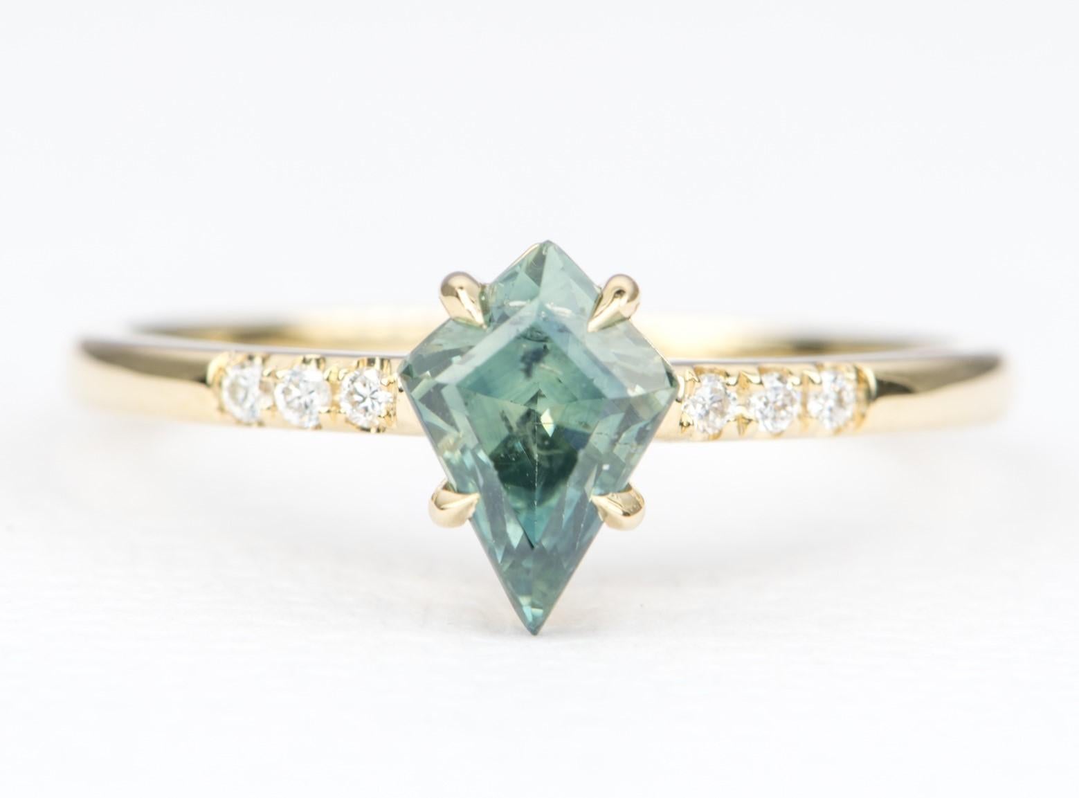 ♥  Solid 14K yellow gold ring set with a kite-shaped sapphire held with diagonal claw prongs, flanked with colorless diamonds on the band
♥  The center sapphire is a stunning teal color that is a mixture of blue and green

♥  Material: 14K yellow
