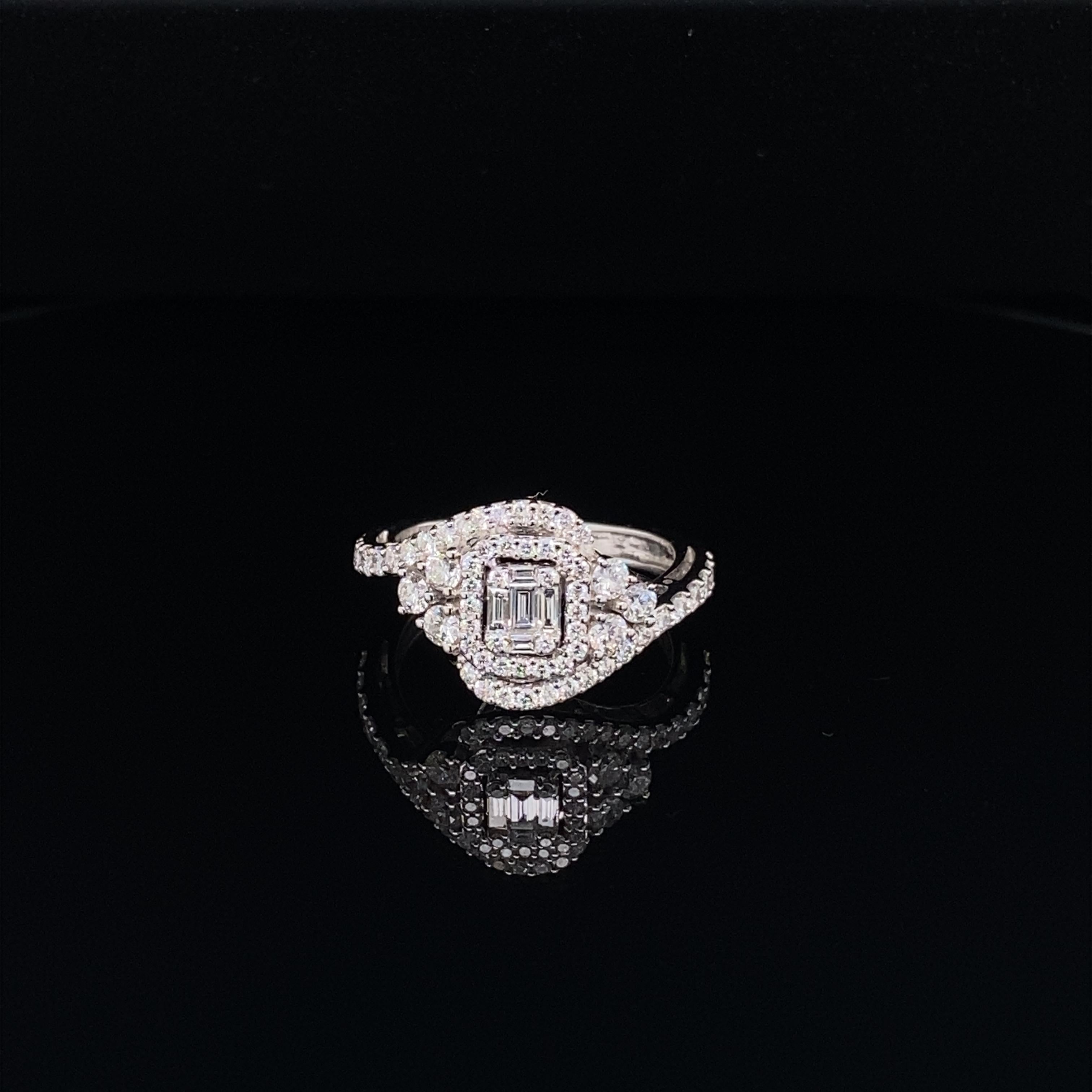 Cette superbe bague présente une magnifique grappe de diamants blancs de taille émeraude, composée de diamants baguettes et ronds, entourée d'une mer de diamants. La grappe de diamants est posée sur une tige en diamant. Cette bague est sertie d'or