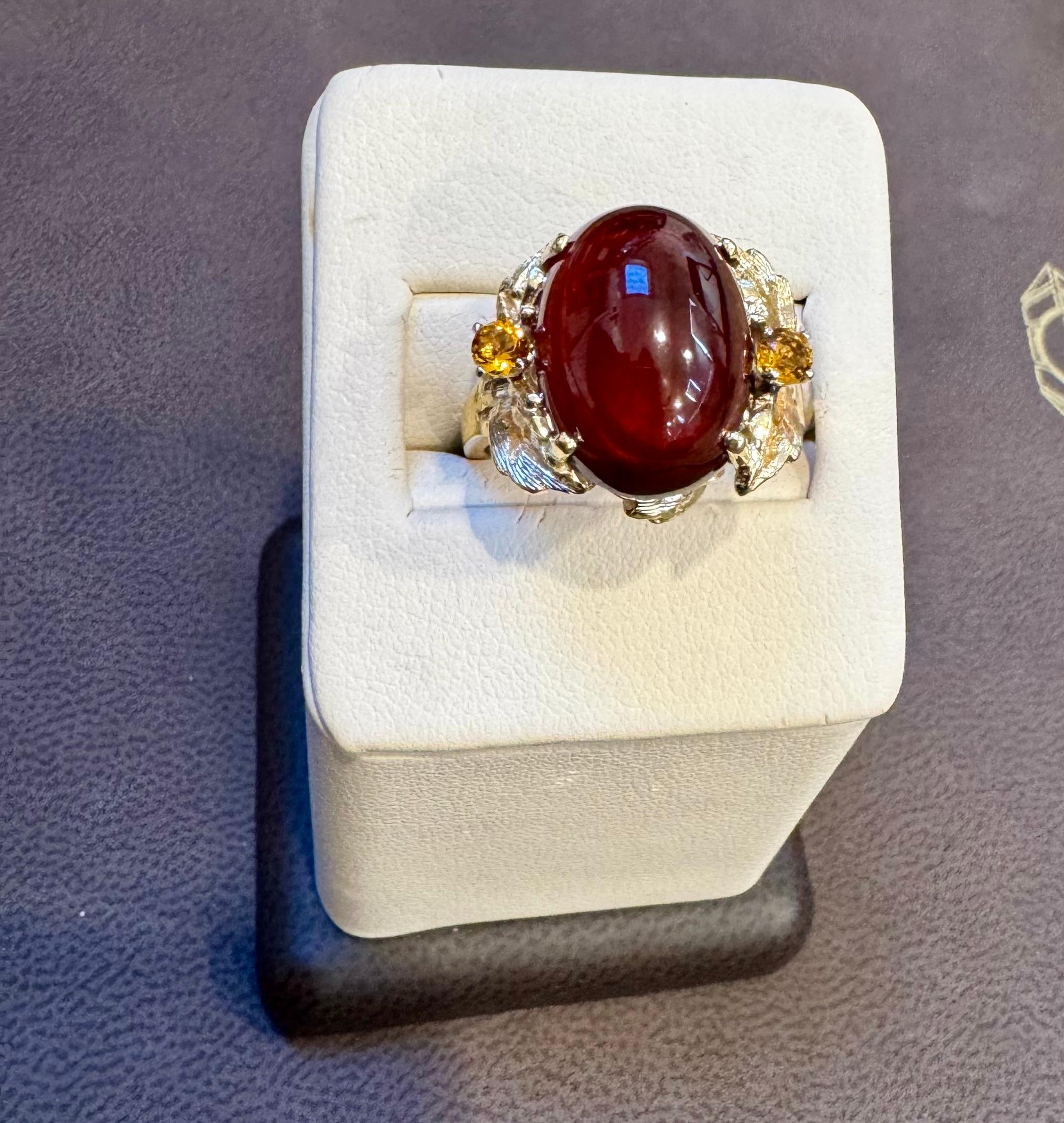 Cette bague de cocktail classique présente un superbe cabochon ovale de grenat naturel avec deux pierres de citrine . Le grenat  est de 10,5 carats et est de qualité 