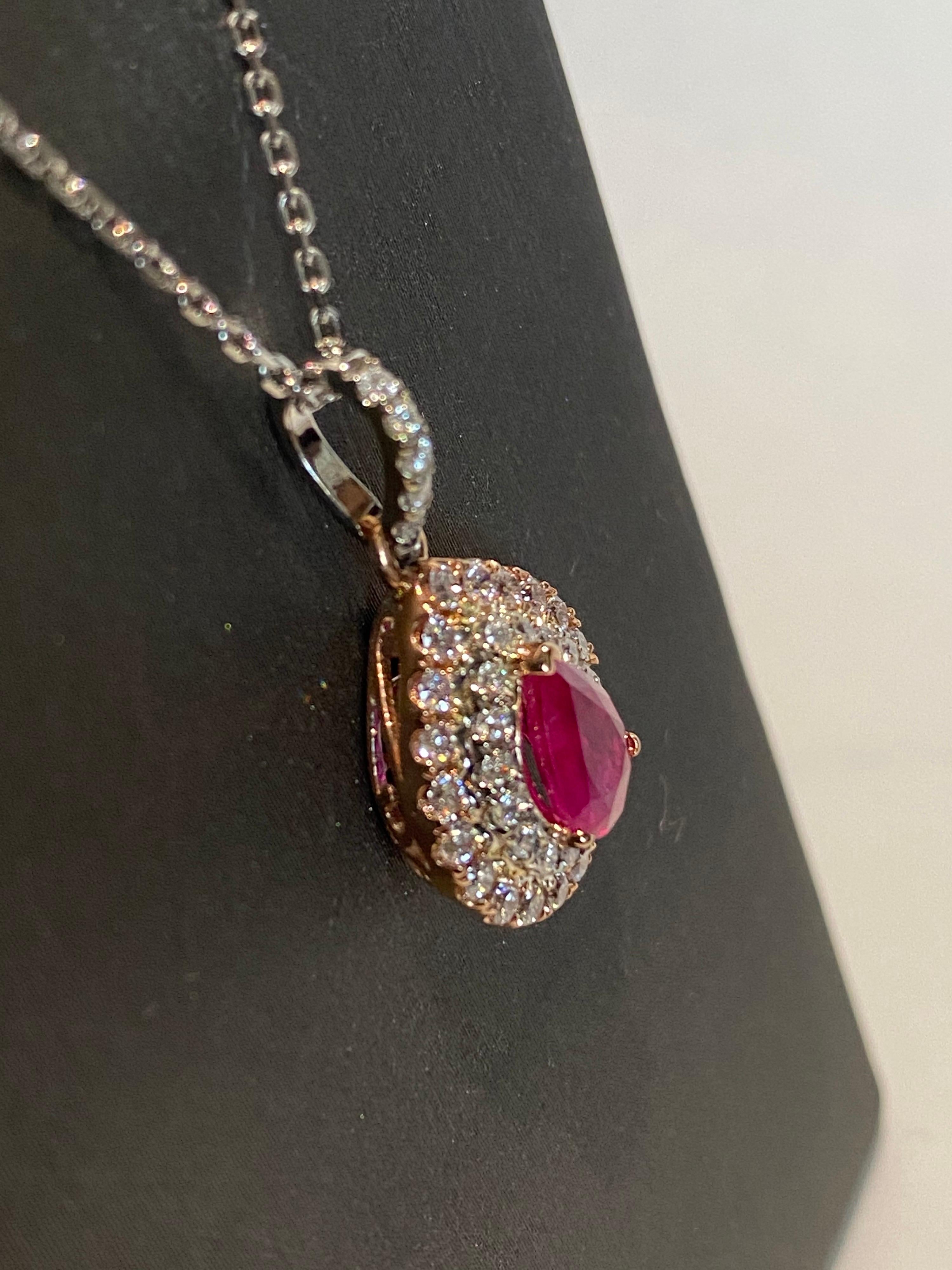 Pear shaped ruby has double halo of pink and white diamonds. Double halo makes the center stone stand out and look bigger. Set in two tone gold, a white gold chain is included. 
Ruby: 1.05ct
White Diamond: 0.23ct
Pink Diamond: 0.39ct
Two Tone Gold:
